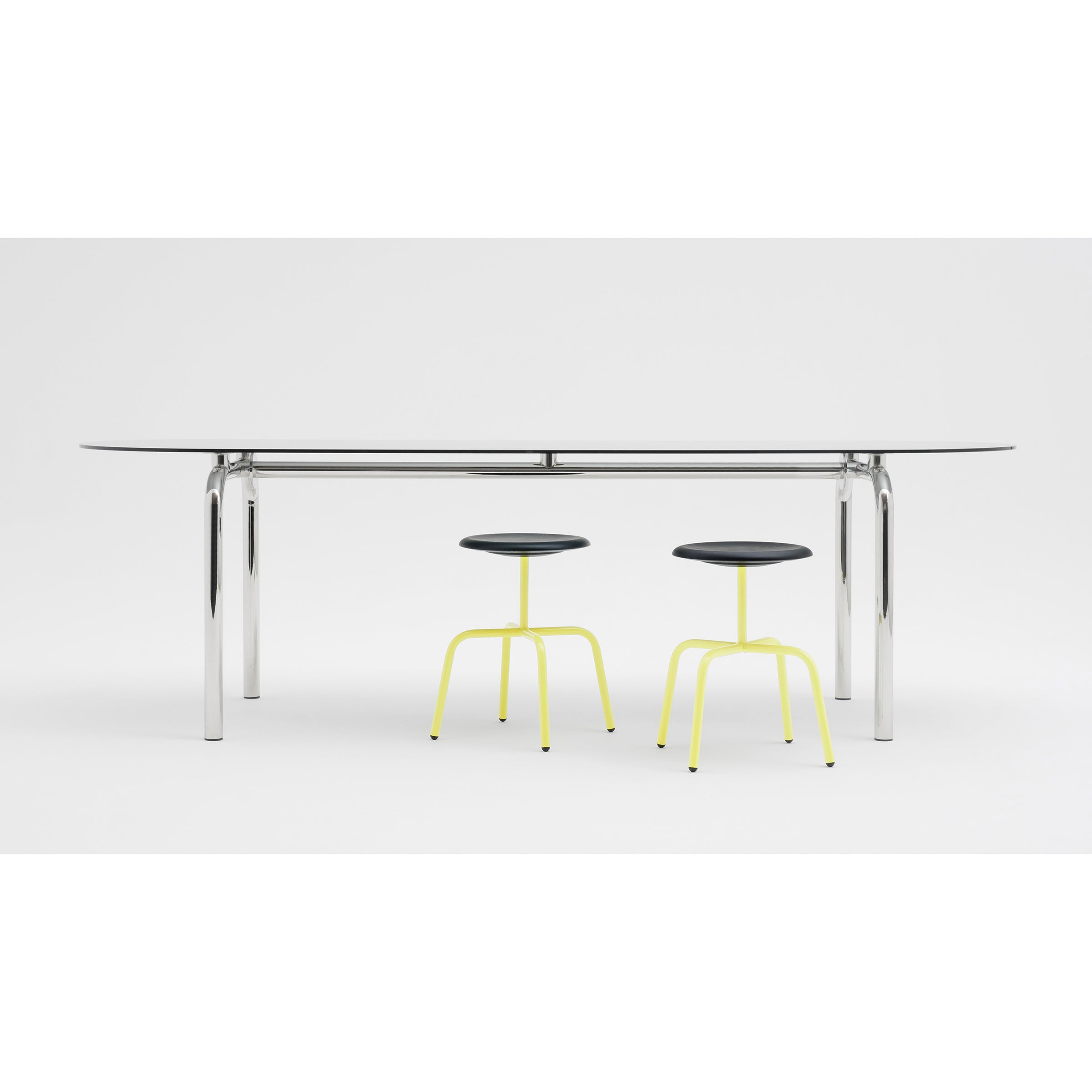 A sleek, modern Piombino Basso Table by Atelier Haussmann with a glossy black top and polished steel tube legs comes with two minimalist stools featuring black seats and vibrant yellow legs, set against a clean white background.