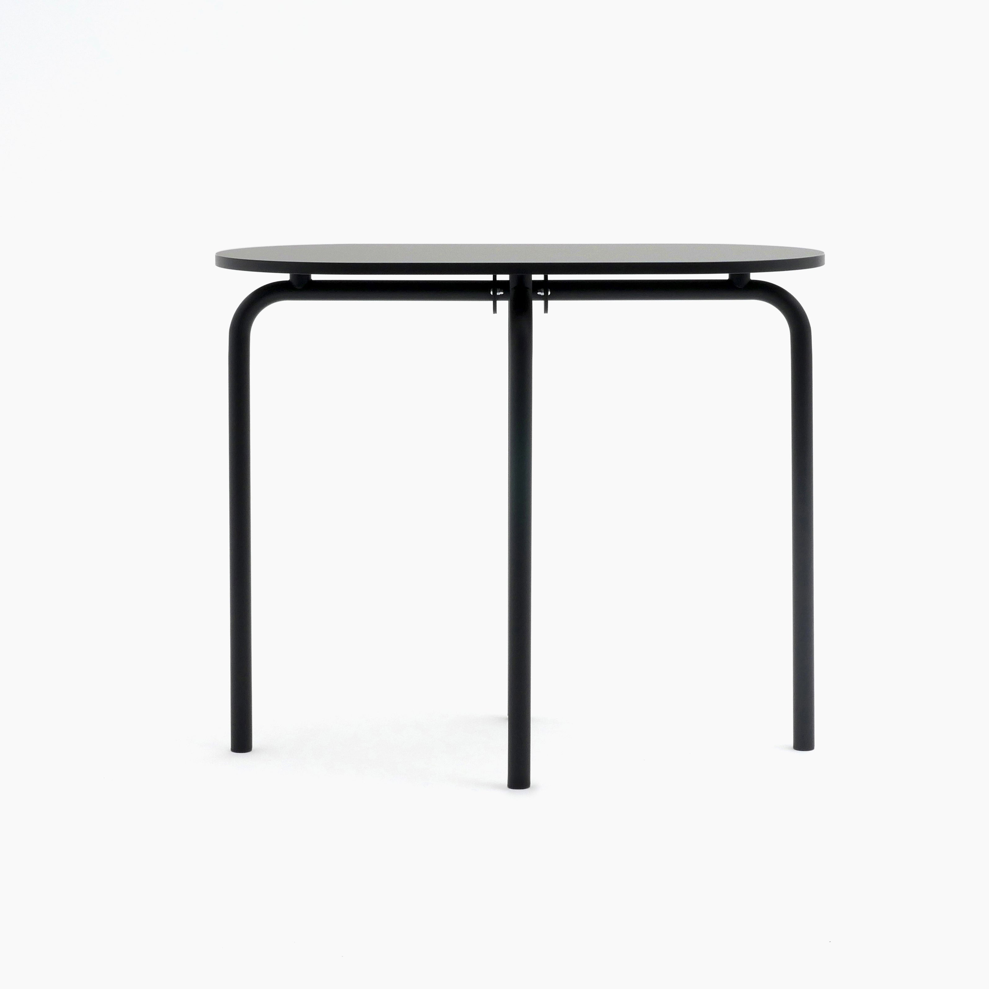 The Piombino Alto 1267 by Atelier Haussmann boasts a minimalist, sleek black design with a round top and three slender legs. Its modern look exudes industrial charm against a white backdrop.