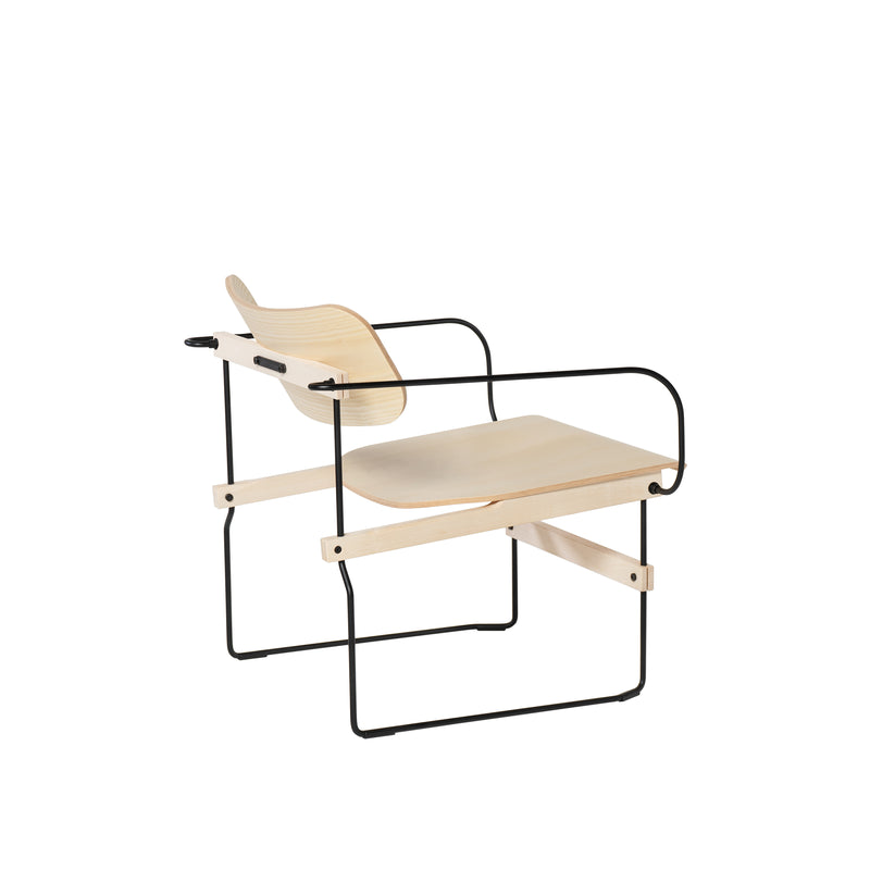 The Moormann Brutissimo is a modern lounge chair with a sleek design, featuring a light molded wood seat and slightly curved backrest for comfort. It boasts thin black metal armrests and a simple, minimalist frame.