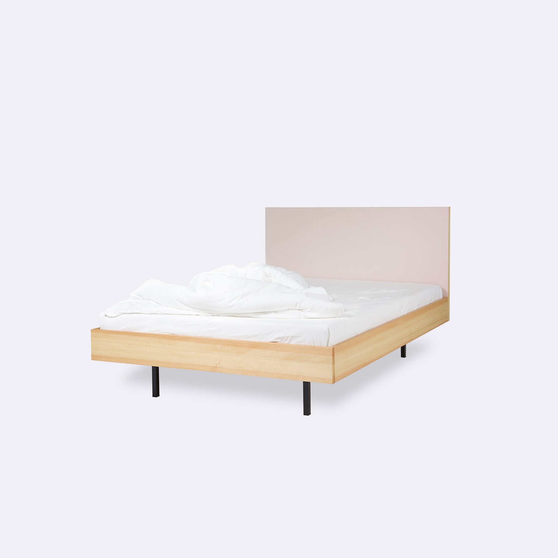 The Bartmann Berlin Unidorm Bed Powder features a sleek design with an oiled pine frame and black steel legs, complemented by crumpled white bedding and a light grey backdrop, offering a minimalistic and inviting sleep space.