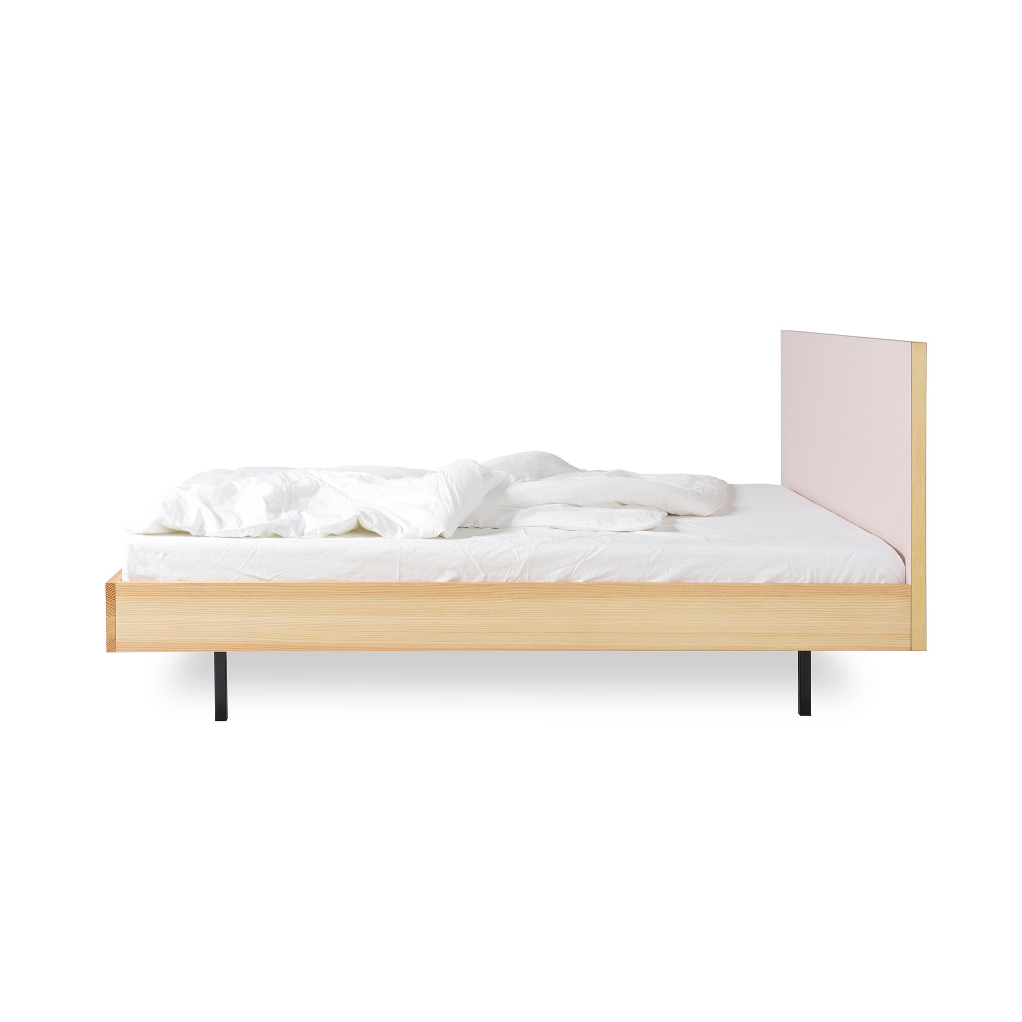 The Bartmann Berlin Unidorm Bed Powder showcases a minimalist design with a high oiled pine headboard, sleek black steel legs, and white bedding. It elegantly stands against a pristine white background, inviting relaxation with its cozy pillows and crumpled duvet.