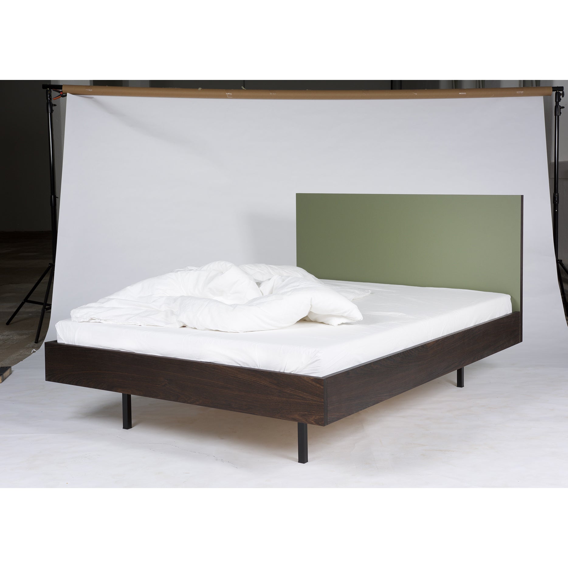 In a neutral setting, the Bartmann Berlin Unidorm Bed Olive is showcased. This modern double bed features a smoked oak frame with black legs and sports a green headboard. Its complemented by a white duvet and pillows, creating a minimalistic and clean look.