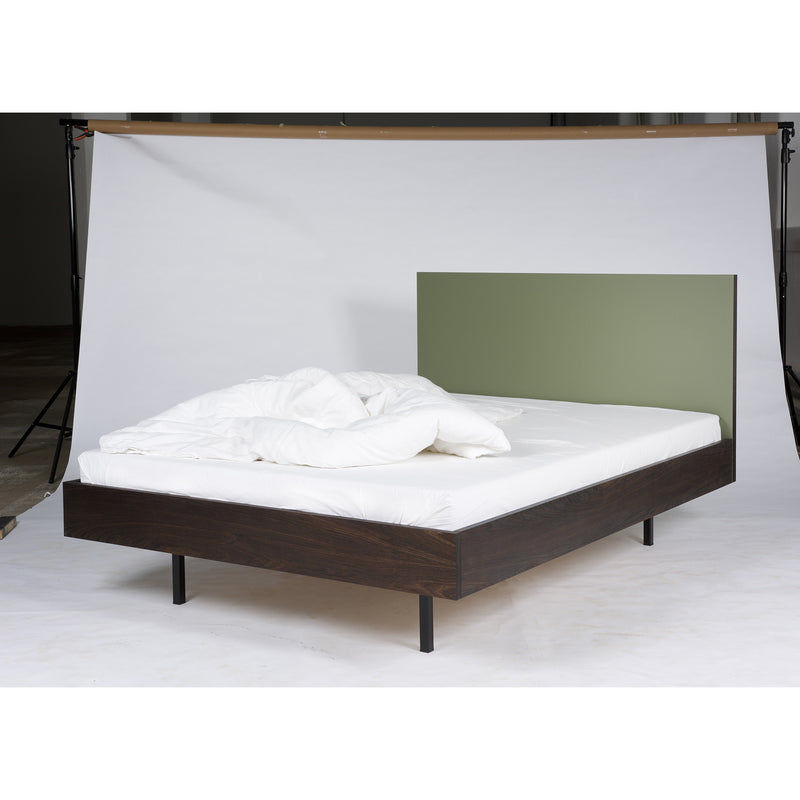 In a neutral setting, the Bartmann Berlin Unidorm Bed Olive is showcased. This modern double bed features a smoked oak frame with black legs and sports a green headboard. Its complemented by a white duvet and pillows, creating a minimalistic and clean look.