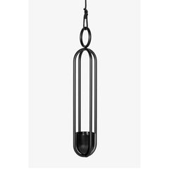 The Blumenampel - Hanging Flower Vase by Atelier Haussmann is a minimalist black metal piece with sleek, elongated vertical bars, a circular top loop, and a small flower holder. Suspended by a black cord, it adds sophistication to any space.