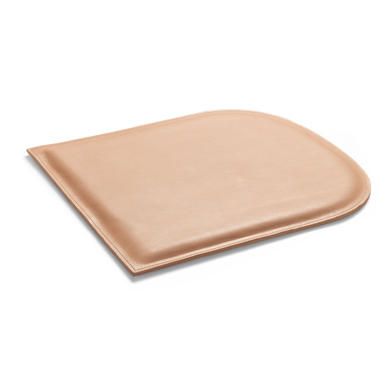 The E15 CU10 GAMAR Cushion, tan in color, boasts a curved top edge and straight sides with a smooth, slightly glossy finish reminiscent of harness leather, displayed against a white background.