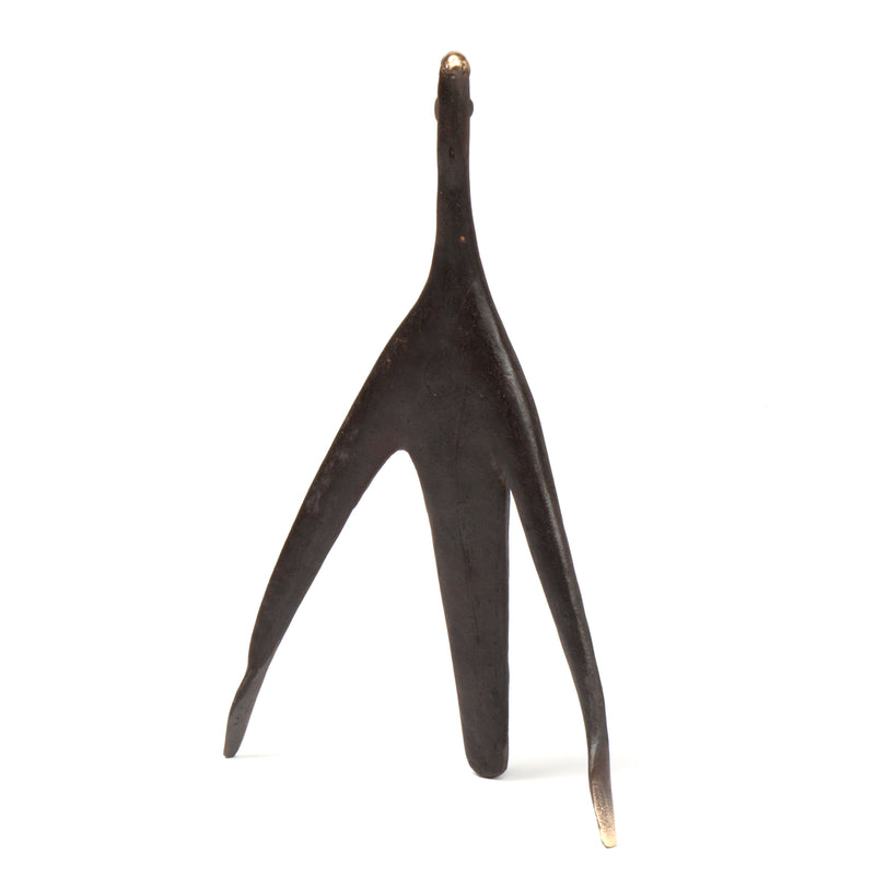Sculpture Architect #4061 by Werkstätte Carl Auböck, a black metal wishbone-shaped piece, stands against a white background. Its textured surface and asymmetrical prongs, casting a shadow, evoke the elegance typical of a Viennese townhouse.