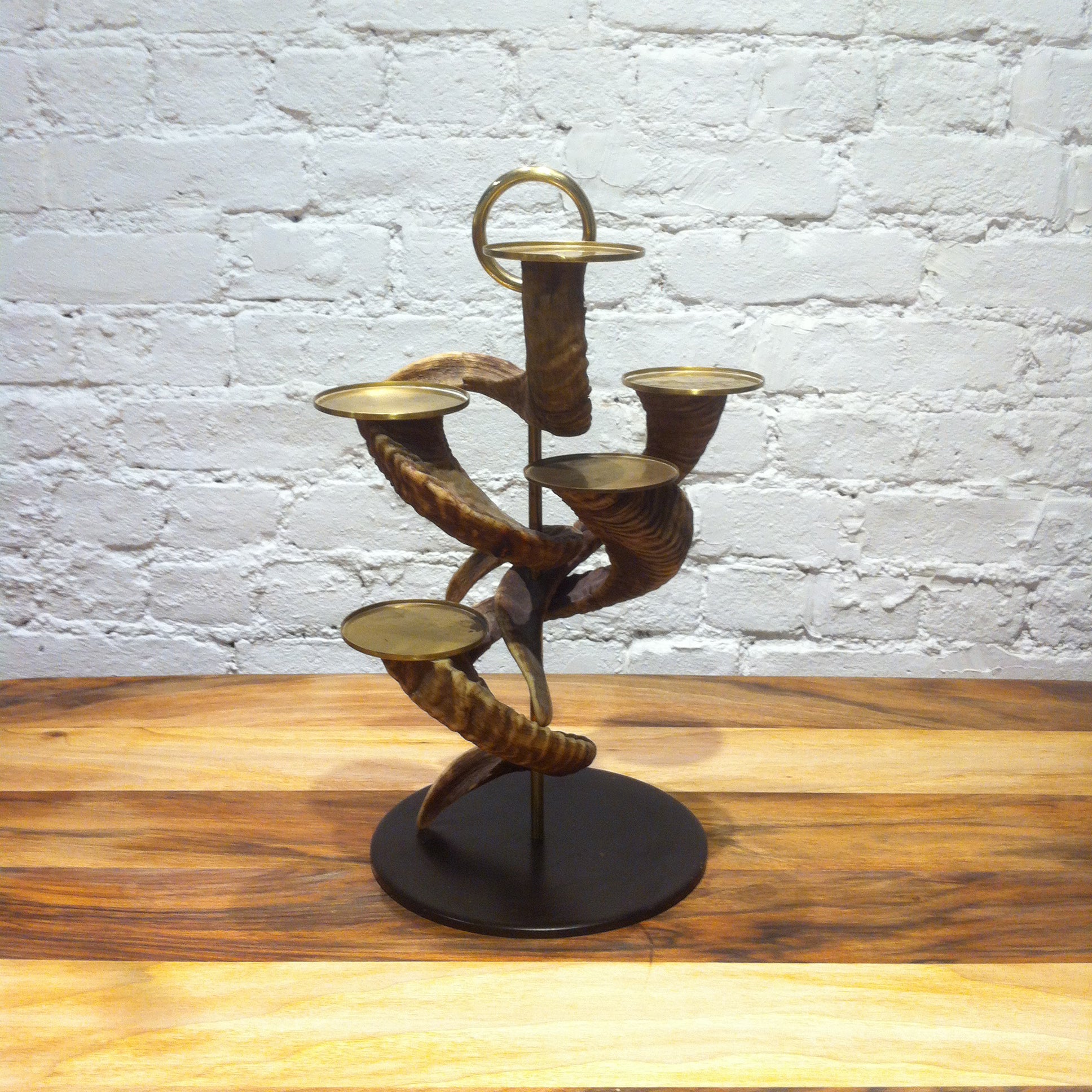 The Vintage Five Horn Candlestick by Werkstätte Carl Auböck elegantly adorns an original Viennese townhouse, showcased against a white brick wall on a wooden surface.