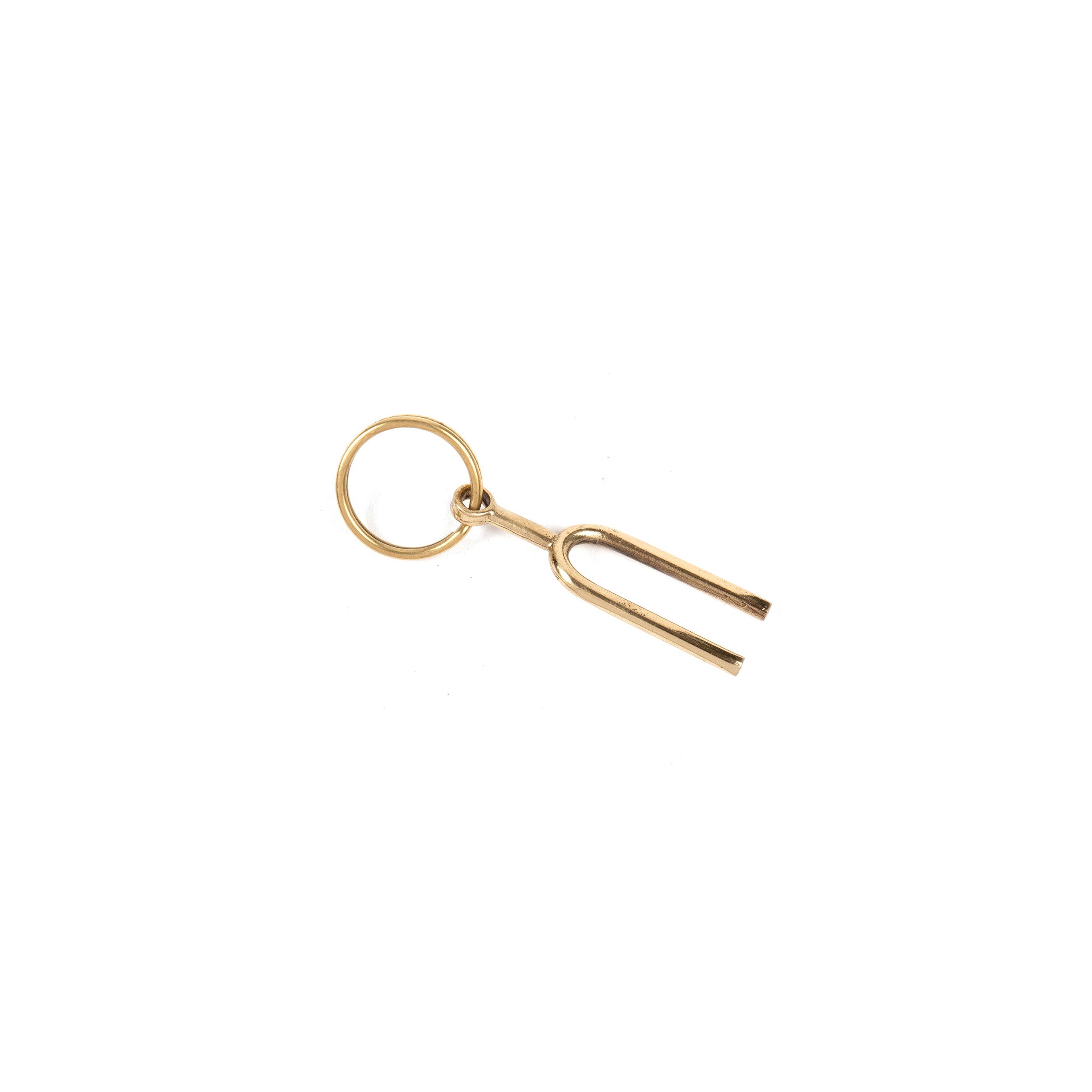 The Keyring Tuning Fork #7225 by Werkstätte Carl Auböck, with its small, golden design, evokes the charm of Carls creations. Its prongs gleam elegantly against a plain white backdrop, akin to timeless Viennese townhouse treasures.