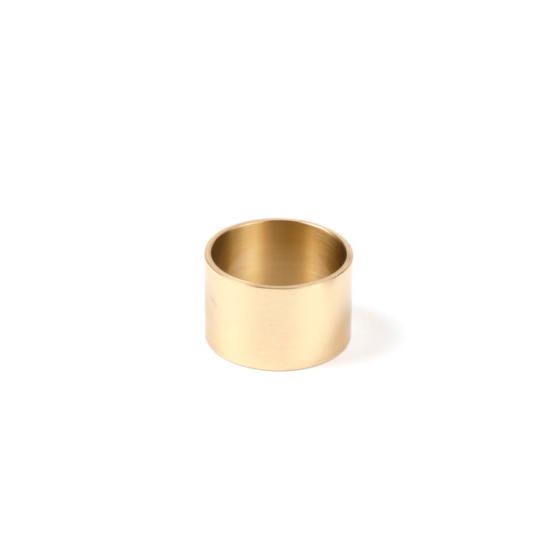 An upright Werkstätte Carl Auböck Egg Cup #7229, a simple cylindrical design in gold color, sits against a plain white background.