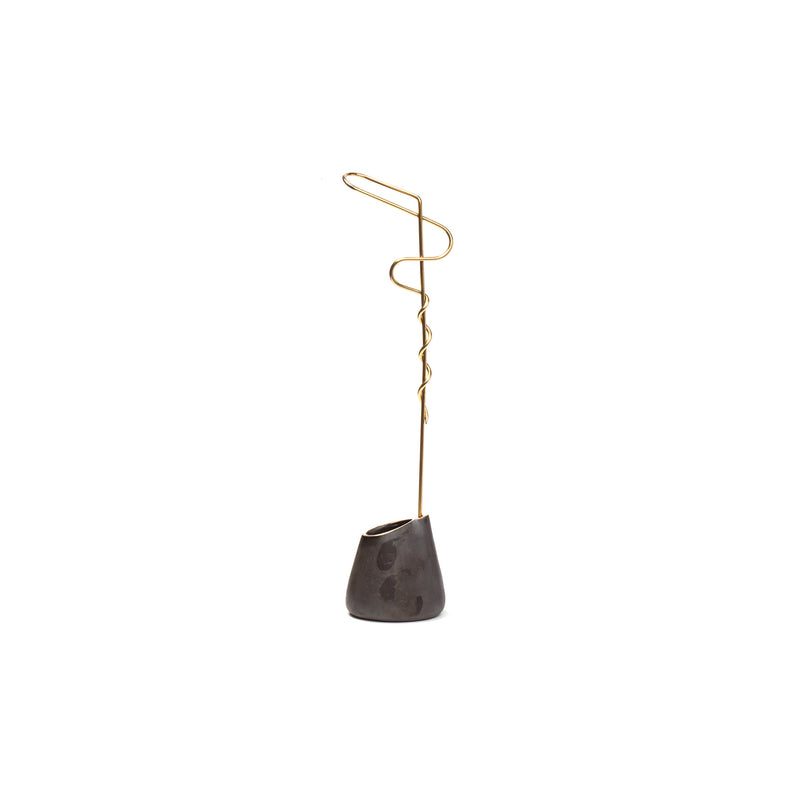 Vase Single Noose #7240 by Werkstätte Carl Auböck is a minimalist, artistic piece featuring a curved brass wire emerging from an irregular gray stone base. The wire spirals at the top, echoing the brands elegance for a modern touch.