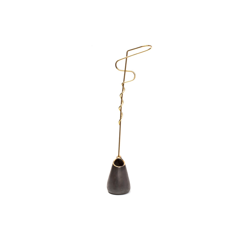 Vase Single Noose #7240 by Werkstätte Carl Auböck is a sleek and modern incense holder with a twisted, gold-colored metal stand on a smooth, dark gray base, offering a minimalist and artistic design that pops against the plain white background.