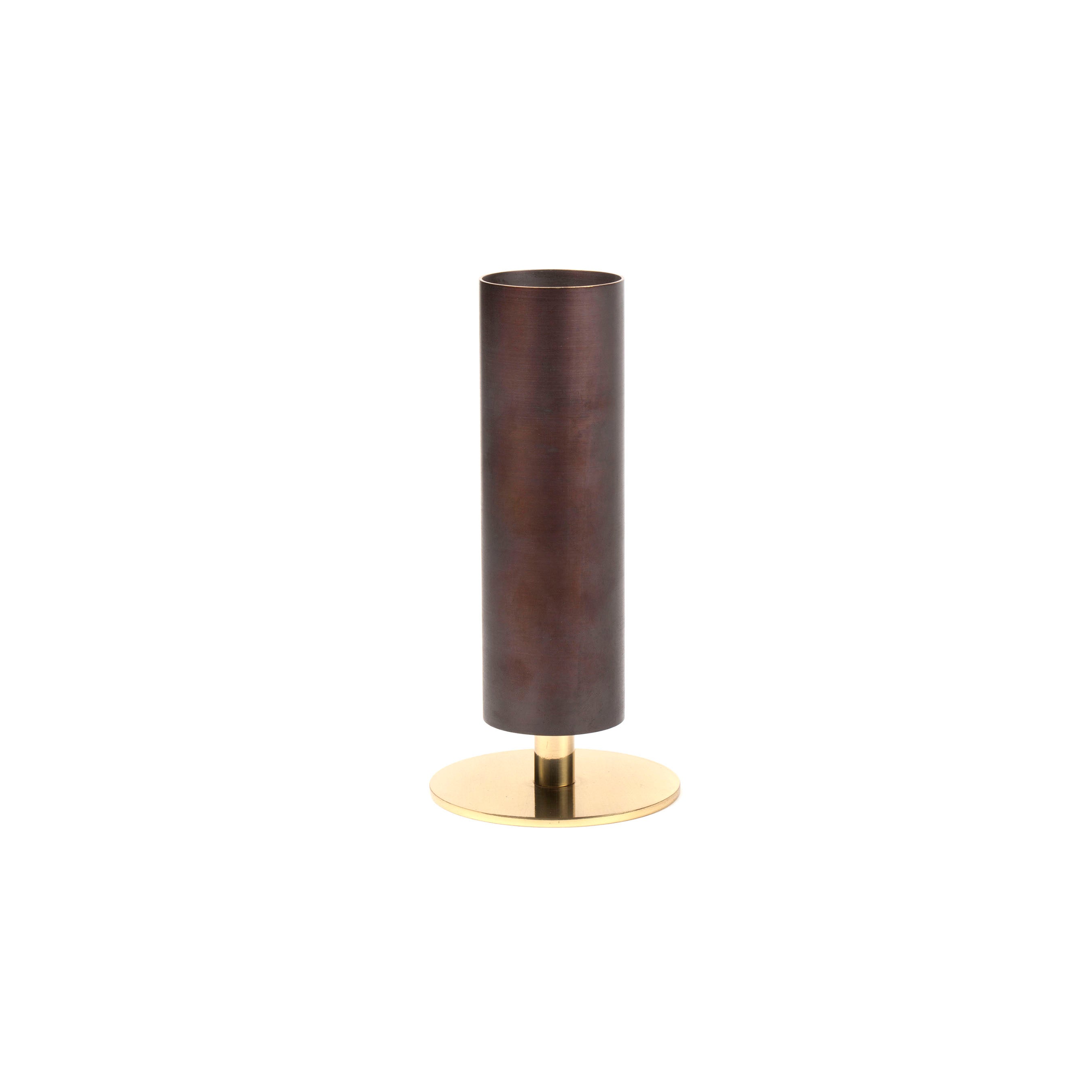 Vase #7247 by Werkstätte Carl Auböck features a sleek, cylindrical brown body with a smooth surface on a round gold base. Its modern design exudes minimalistic elegance reminiscent of the Viennese workshop, beautifully set against a plain white background.