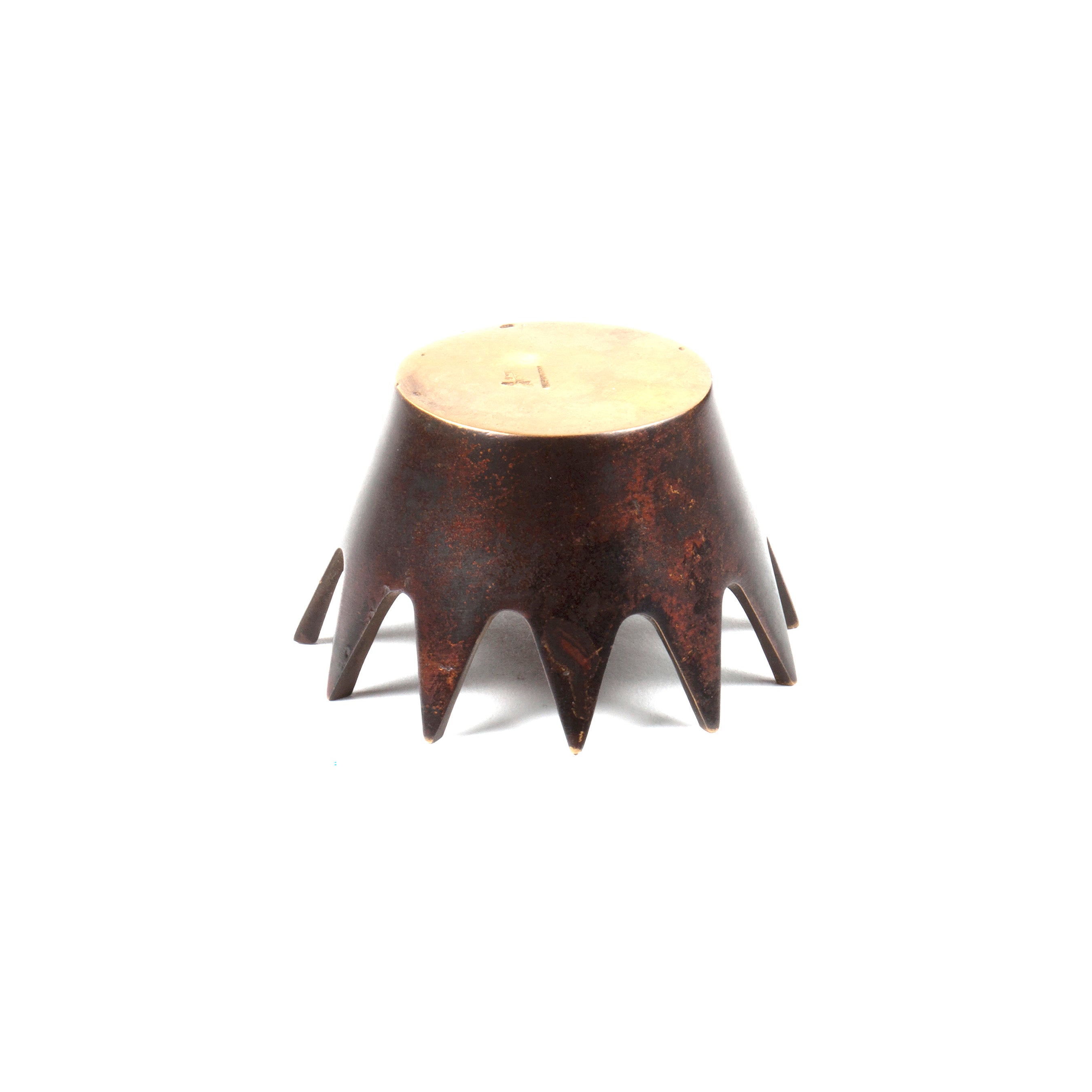 The Ashtray Crown #3600 from Werkstätte Carl Auböck features a round design with a beige top and brown sides resembling a chocolate cake. Large star-shaped points around the base create a spiky look, set against a plain white background.