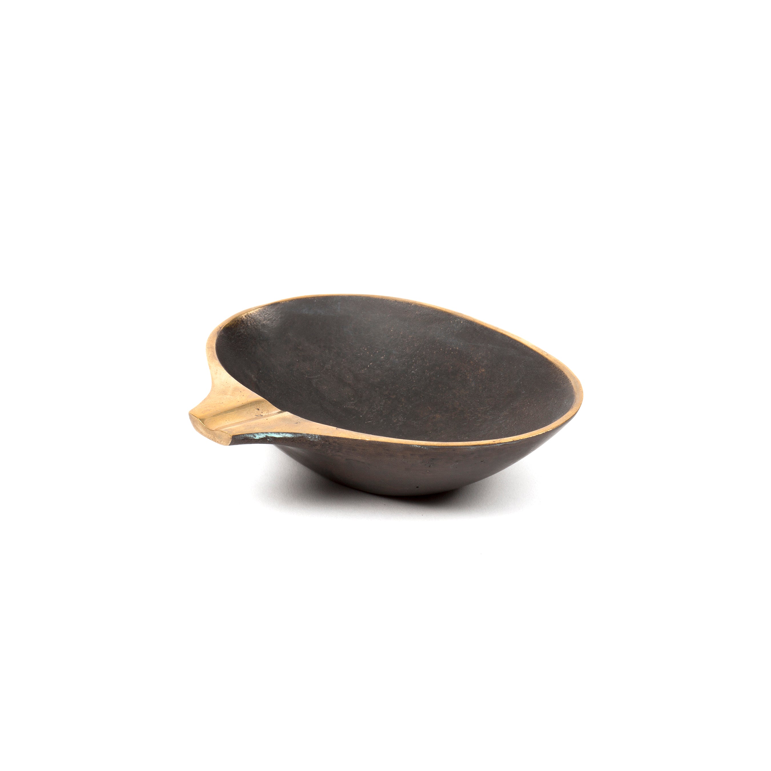 The Dish #4308 by Werkstätte Carl Auböck is a shallow, round black bowl with a tan rim and small protruding handle, showcased on a plain white background.