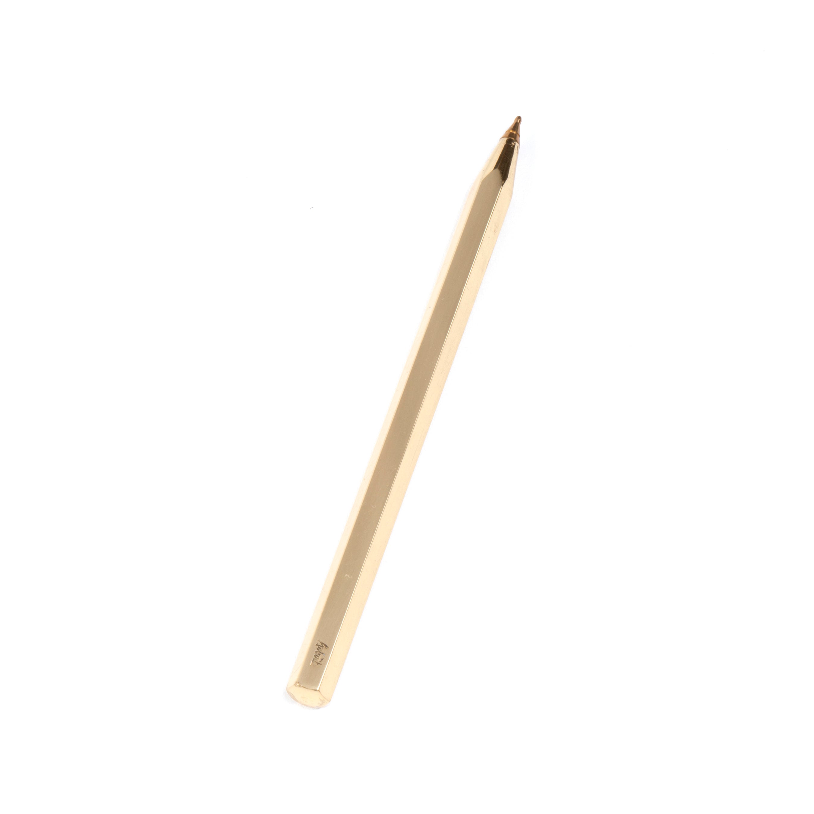 The Ball Point #5800 by Werkstätte Carl Auböck, with its sleek, gold-colored hexagonal design and pointed tip angled on a white background, embodies minimalist elegance and modern sophistication reminiscent of refined Viennese townhouse aesthetics.
