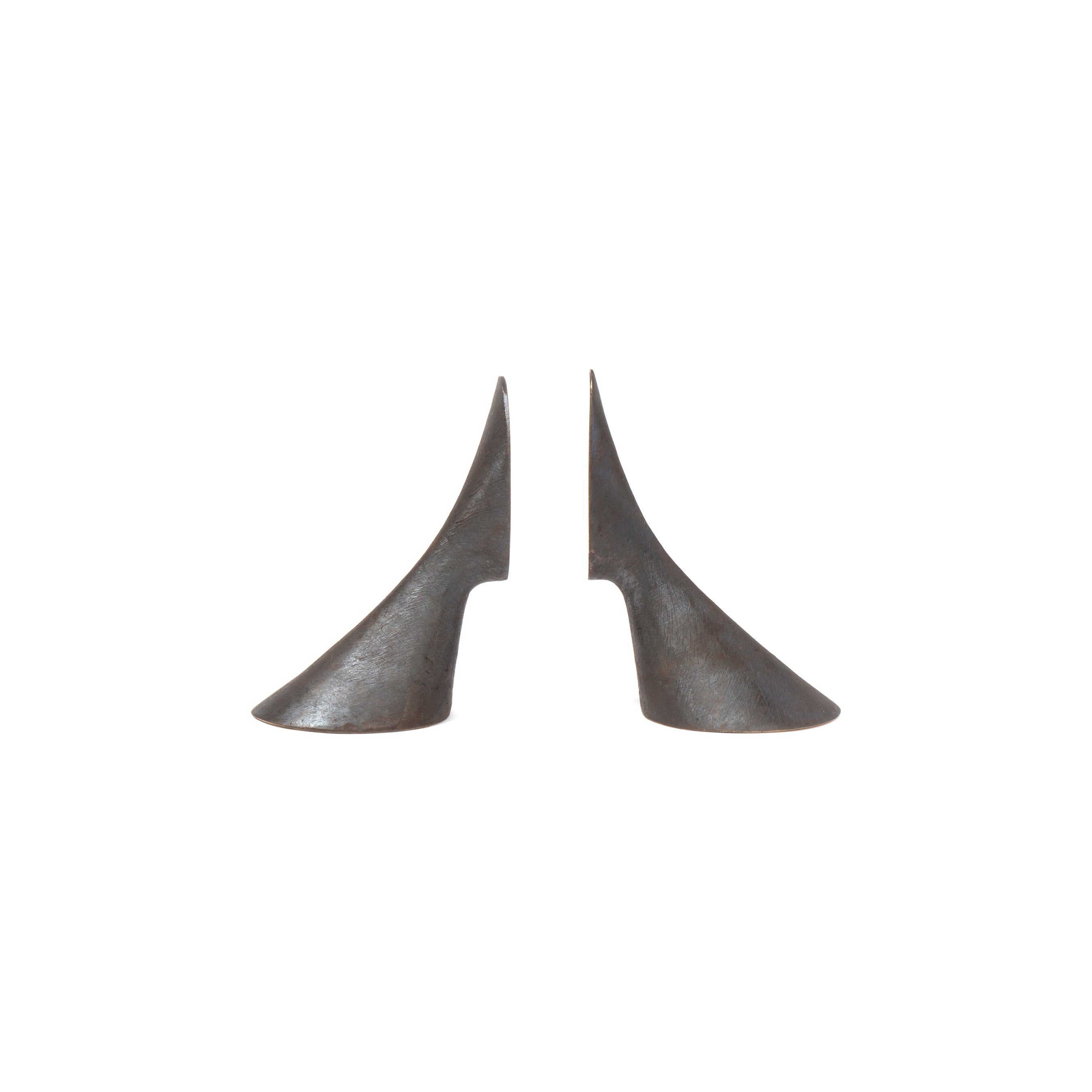 The Pair of Bookends #3651 by Werkstätte Carl Auböck, crafted from gleaming brass in a smooth, curved abstract design resembling elongated cones with a notch on one side, evoke the brands elegance as they face each other against a plain white background.