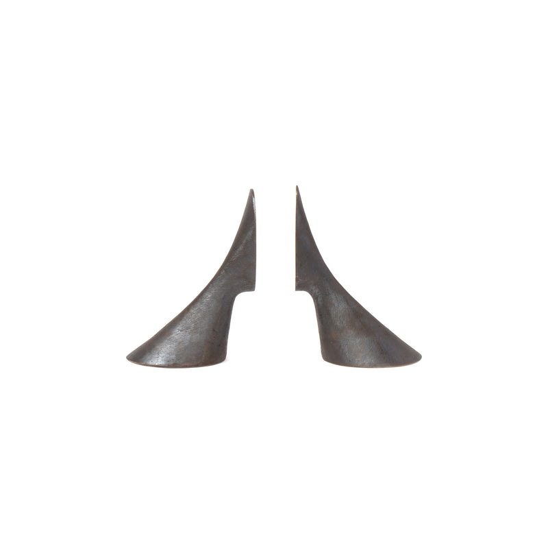 The Pair of Bookends #3651 by Werkstätte Carl Auböck, crafted from gleaming brass in a smooth, curved abstract design resembling elongated cones with a notch on one side, evoke the brands elegance as they face each other against a plain white background.
