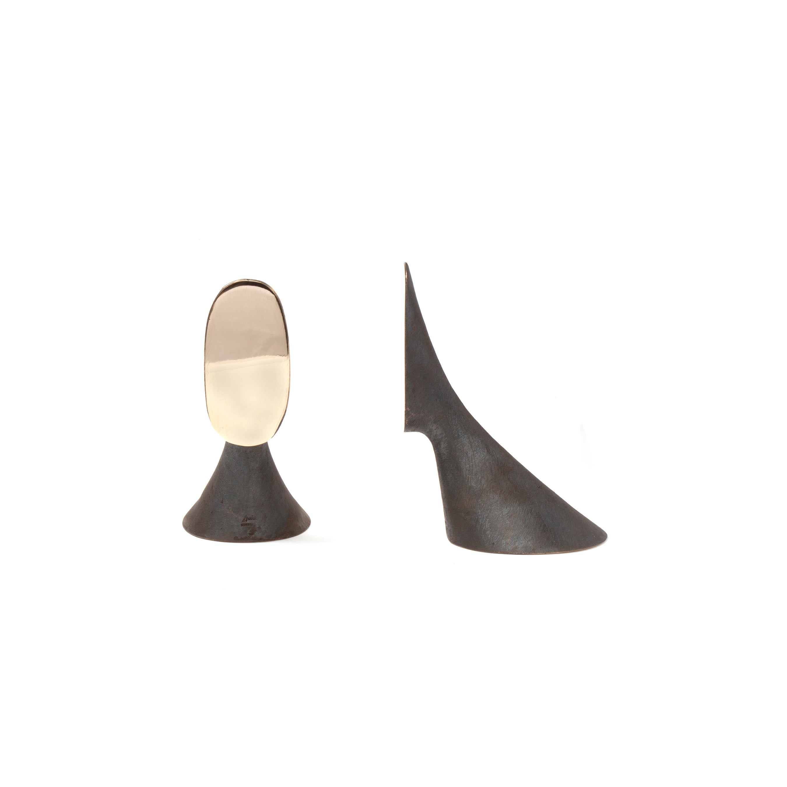 The Pair of Bookends #3651 by Werkstätte Carl Auböck features a minimalist black design with an oval reflective surface on one side and a smooth, curved back on the other. Its wide, slightly textured base resembles Wiener Bronzen craftsmanship, displayed against a plain white background.