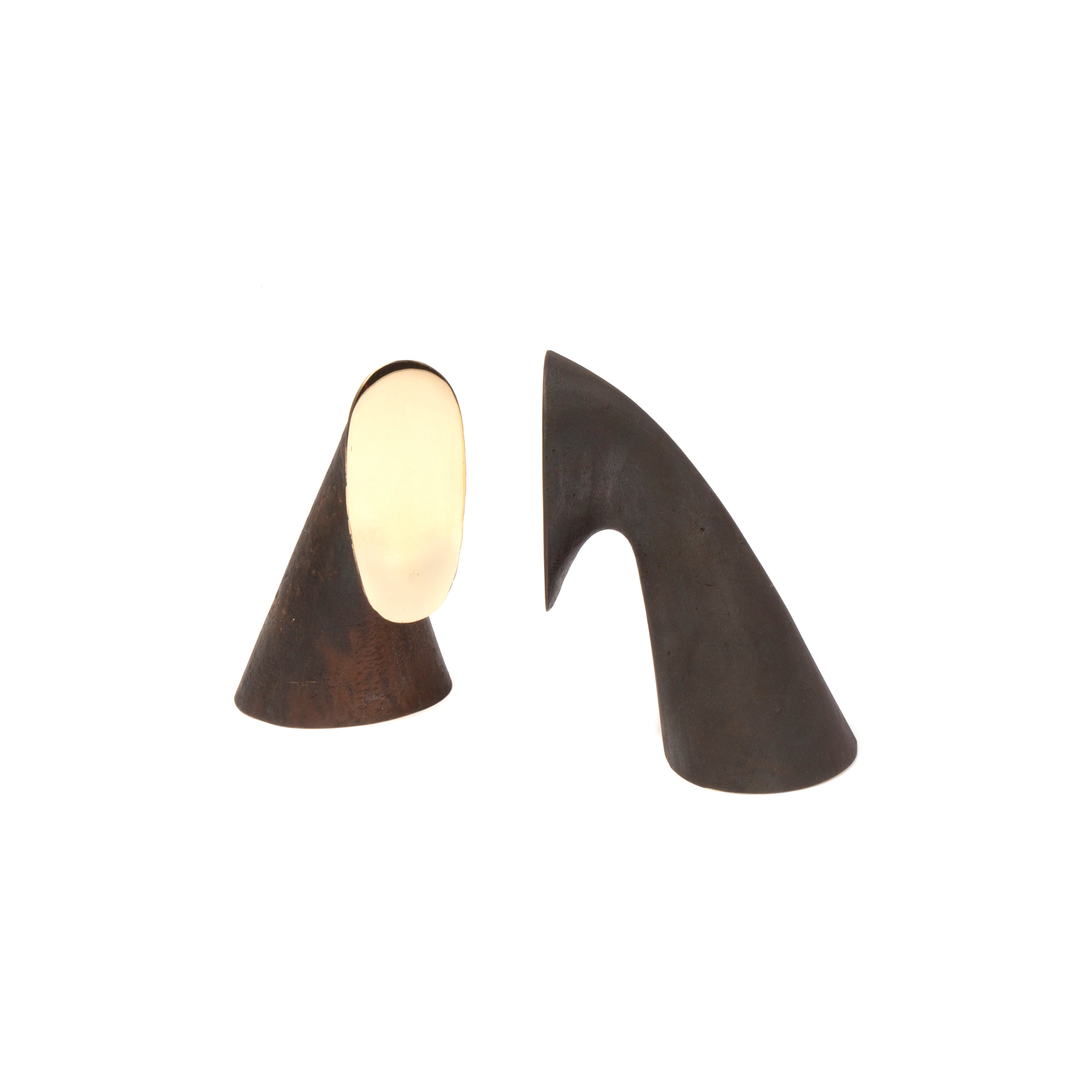 The Werkstätte Carl Auböck Pair of Bookends #3654 feature two abstract, sculpture-like forms: the left is a brown cone with a reflective oval surface, and the right is a dark, curved shape resembling a bent horn. Both stand elegantly against a plain white background.