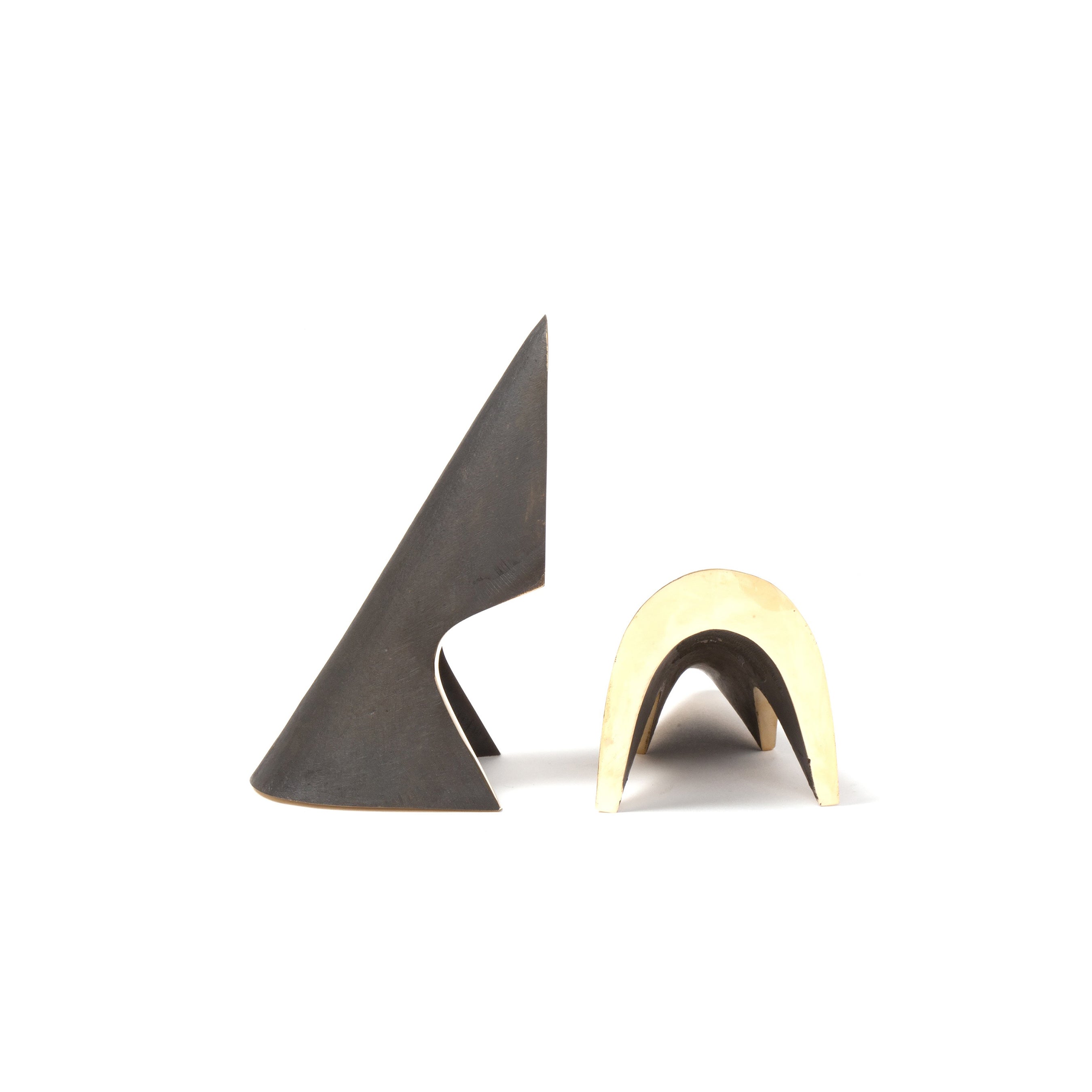 Pair of Bookends #4099 by Werkstätte Carl Auböck captures the iconic style with two abstract metal sculptures on a white background: the left is dark, angular, and sharp-pointed, while the right resembles Wiener Bronzen with a smaller, curved form in a smooth, light tone.