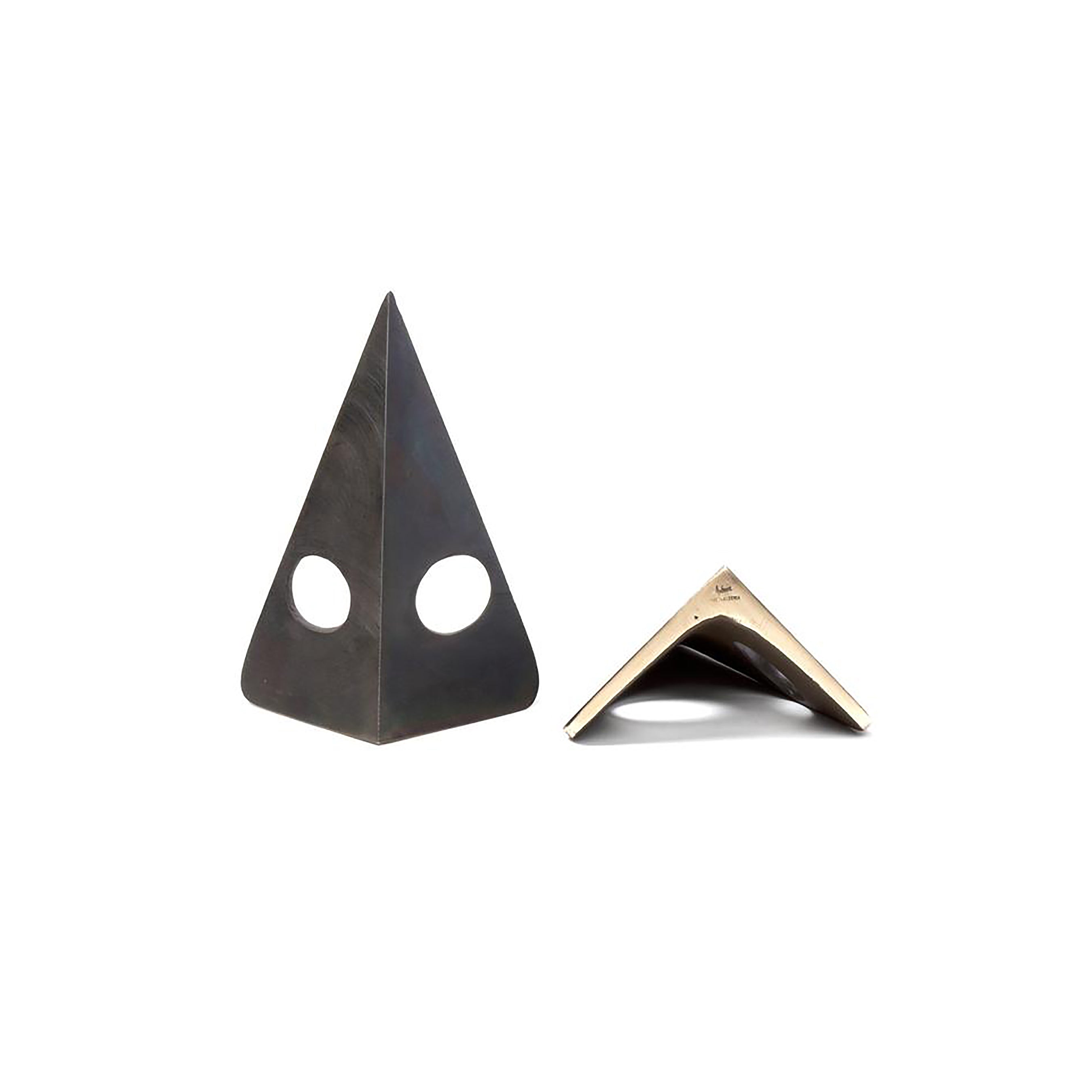 The Werkstätte Carl Auböck Pair of Bookends #4100 features two triangular pieces with large circular cutouts, set against a white backdrop. One is upright, and the other tilts to reveal a metallic finish inspired by Carl Auböcks classic Viennese workshop designs.