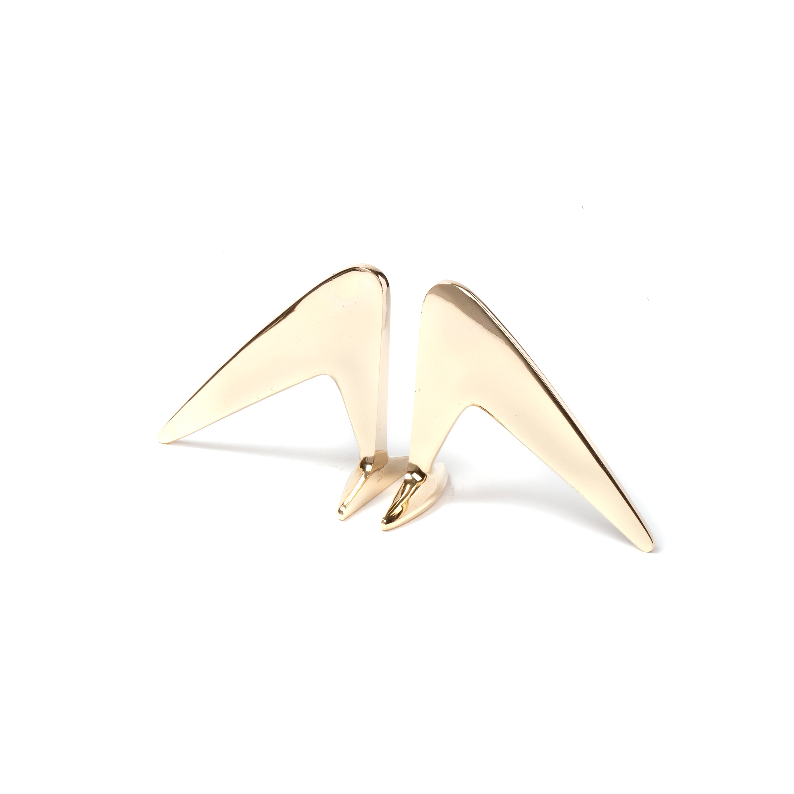 A pair of sleek, gold, triangular Werkstätte Carl Auböck bookends (#4630) with a modern geometric design, reminiscent of Viennese elegance, are shown against a plain white background with their pointed ends angled slightly upwards.