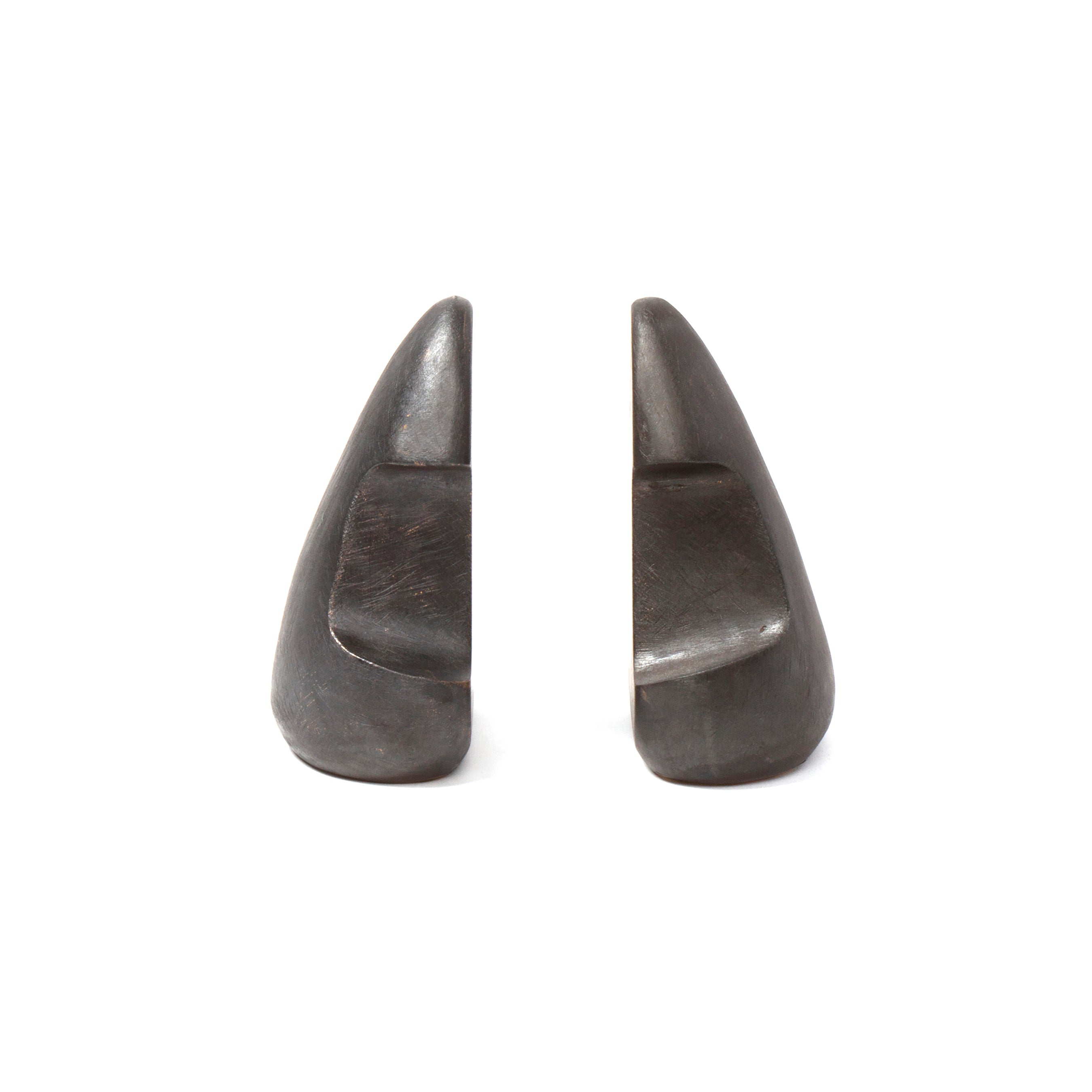 The Pair of Bookends #4637 by Werkstätte Carl Auböck features two sleek, dark stone pieces shaped like abstract mountains, arranged against a plain white background. They embody the timeless elegance characteristic of an Auböck design and evoke the style of a Viennese townhouse.