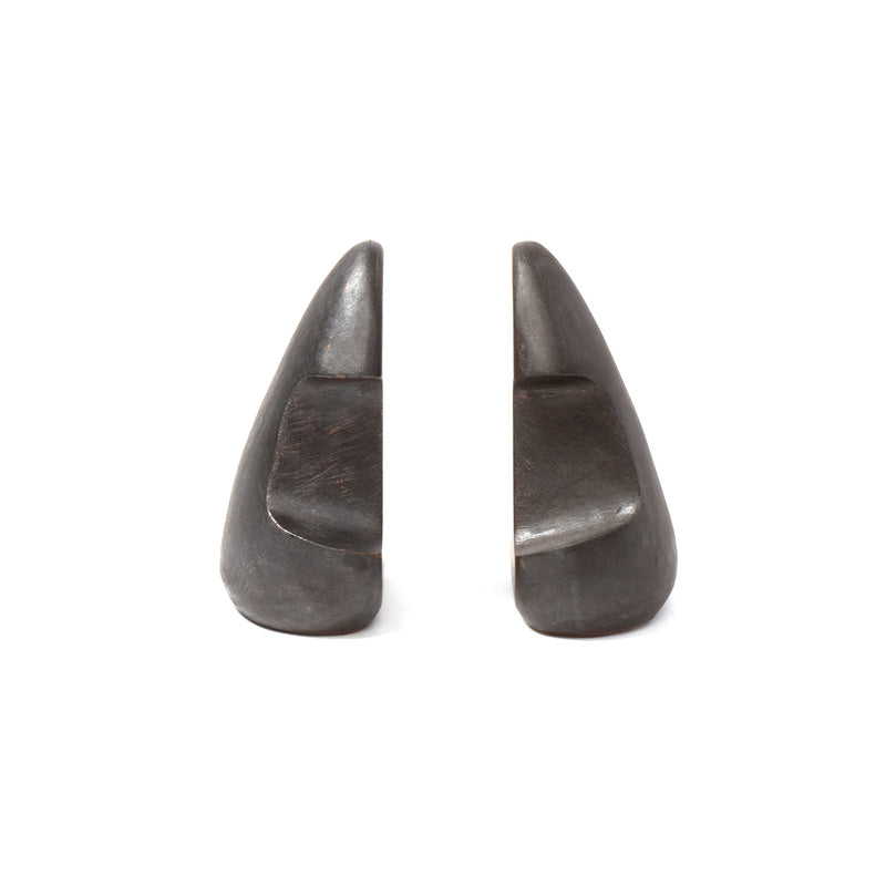 The Pair of Bookends #4637 by Werkstätte Carl Auböck features two sleek, dark stone pieces shaped like abstract mountains, arranged against a plain white background. They embody the timeless elegance characteristic of an Auböck design and evoke the style of a Viennese townhouse.