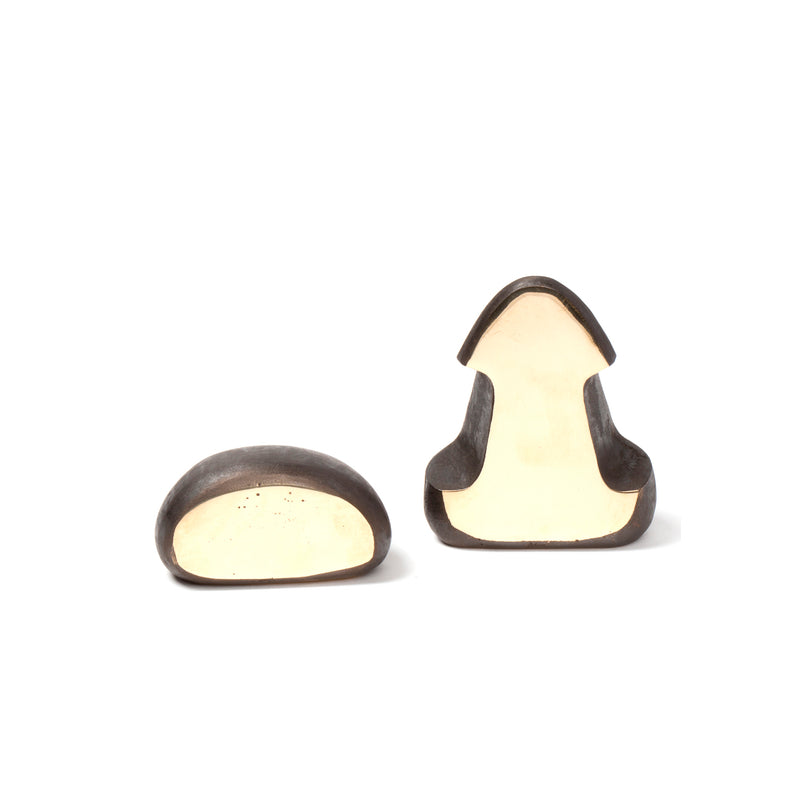 The Pair of Bookends #4637 by Werkstätte Carl Auböck features two ceramic sculptures, one rounded and resting sideways, the other upright and geometrically abstract with a smooth dark exterior and light beige interior, reflecting Viennese townhouse elegance.