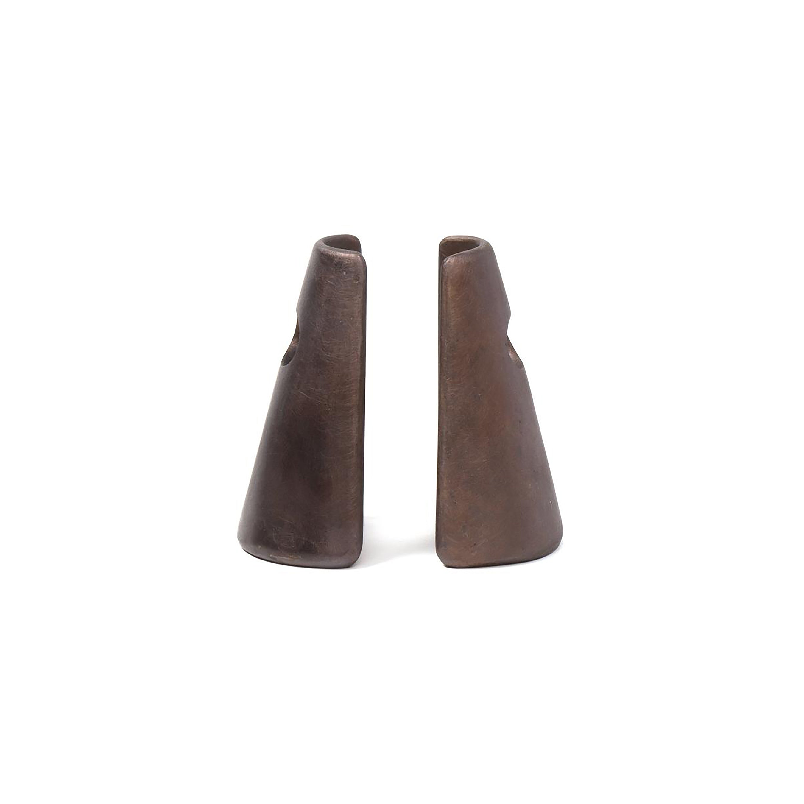 The Pair of Bookends #4843 by Werkstätte Carl Auböck feature sculpted, brown metal forms with smooth, tapered designs that evoke Wiener Bronzen artistry. They face each other on a white background, resembling elongated cones with precise cutouts near the top.