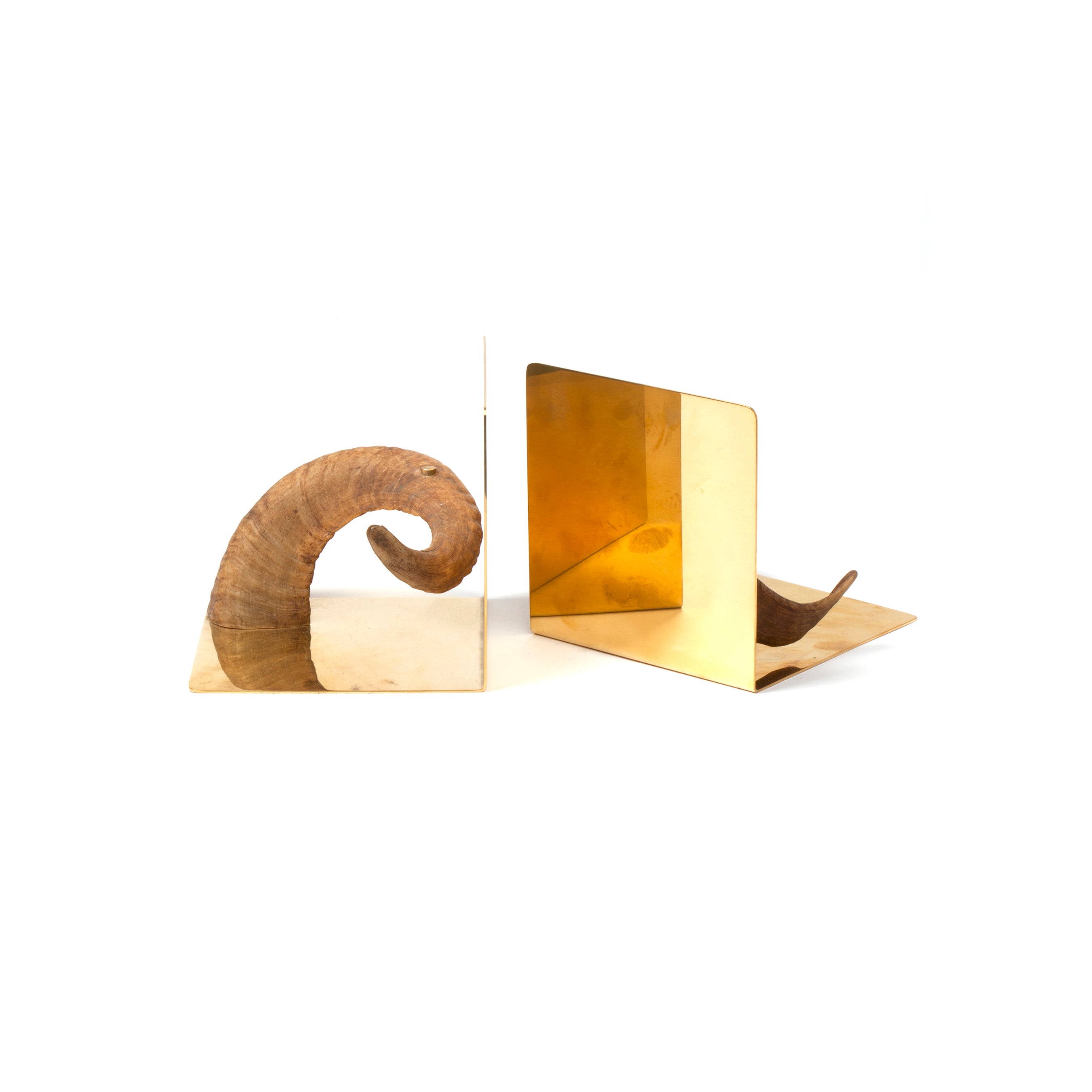 The timeless elegance of Werkstätte Carl Auböcks design is captured in Pair of Bookends #5673, featuring two polished, reflective bookends on a white background. The left displays a curled rams horn on a gold-toned base, while the right showcases a clean design with matching accents.