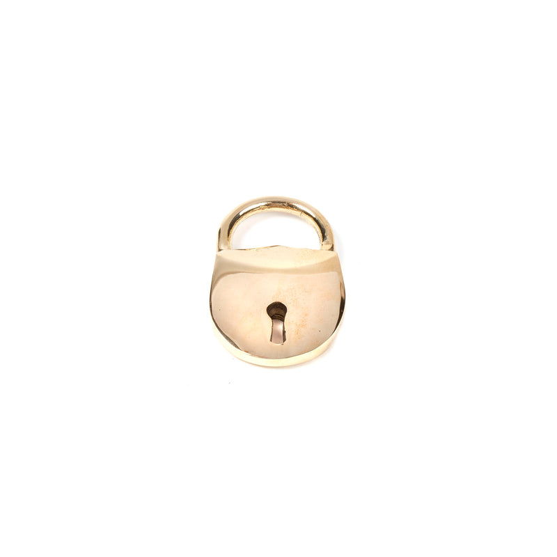 Close-up of the Bottle Opener Lock #4666 by Werkstätte Carl Auböck, a shiny brass padlock with a keyhole, reminiscent of Viennese townhouse craftsmanship, set against a plain white background.