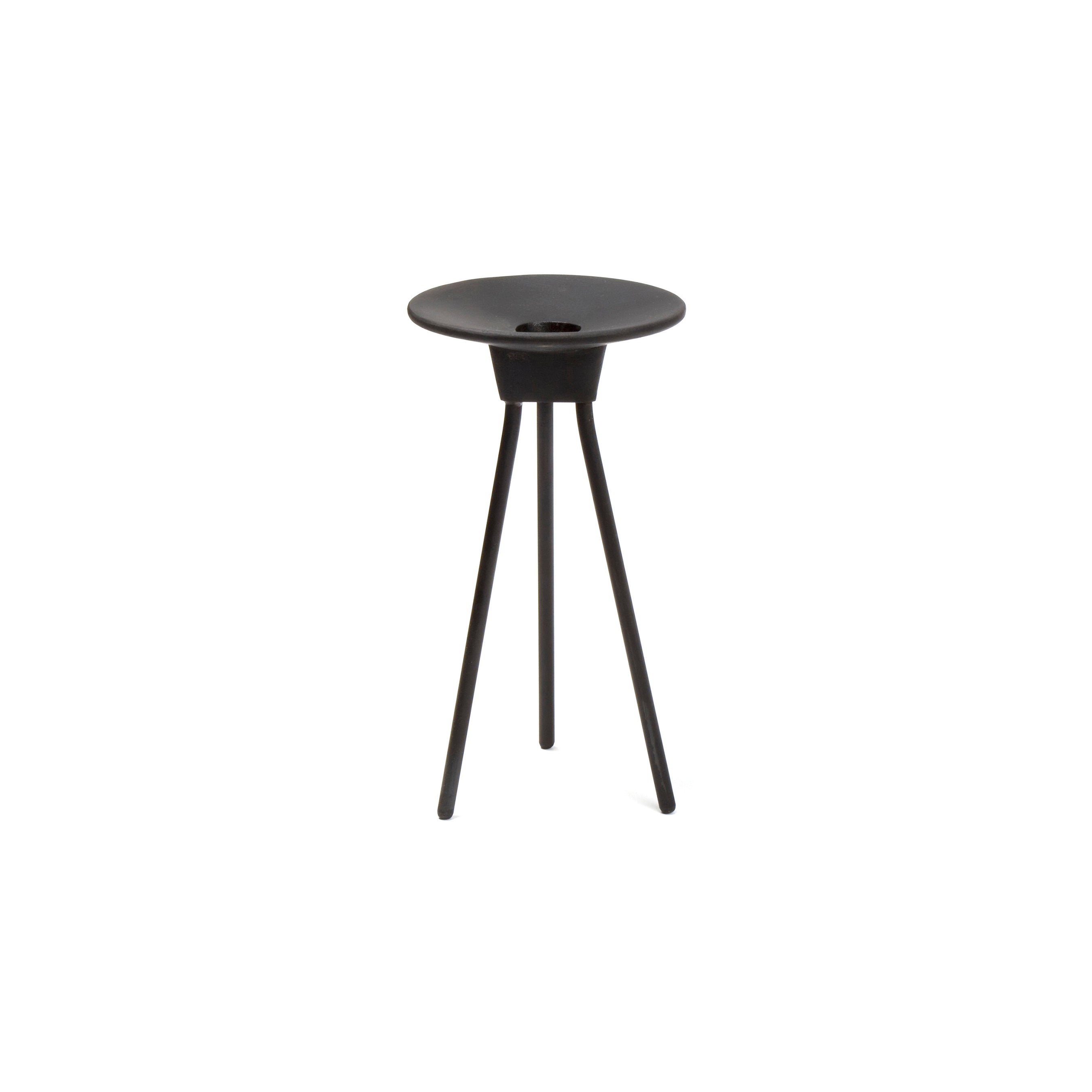 A sleek black tripod table with a round, slightly concave top echoes the minimalist elegance of Carl Auböcks work, reminiscent of functional art at the Triennale di Milano.