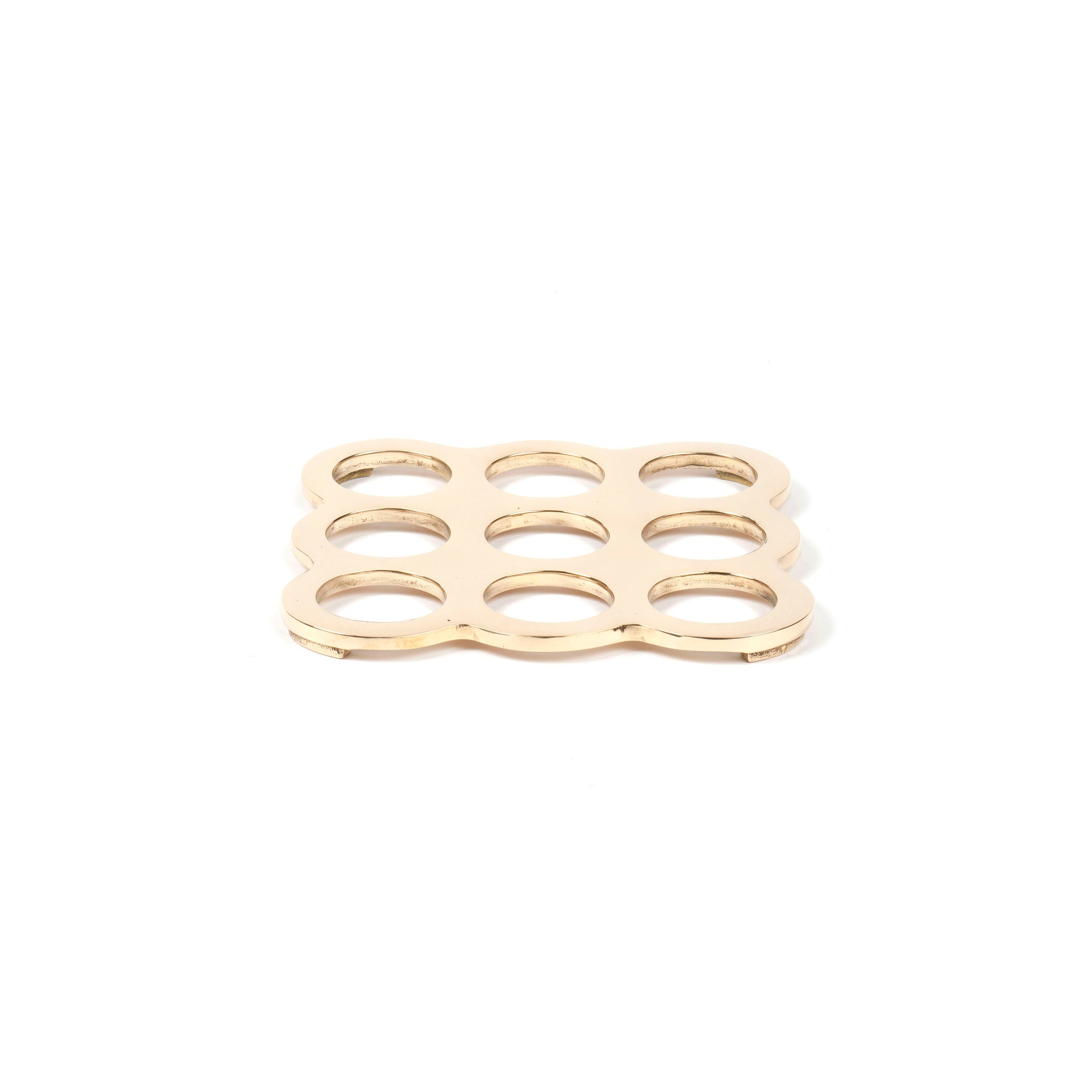 Coaster #5506 by Werkstätte Carl Auböck is a gold, rectangular trivet featuring a grid of nine circular cutouts in three rows and columns. It reflects Viennese craftsmanship with rounded corners and a polished finish characteristic of Carl Auböcks style.