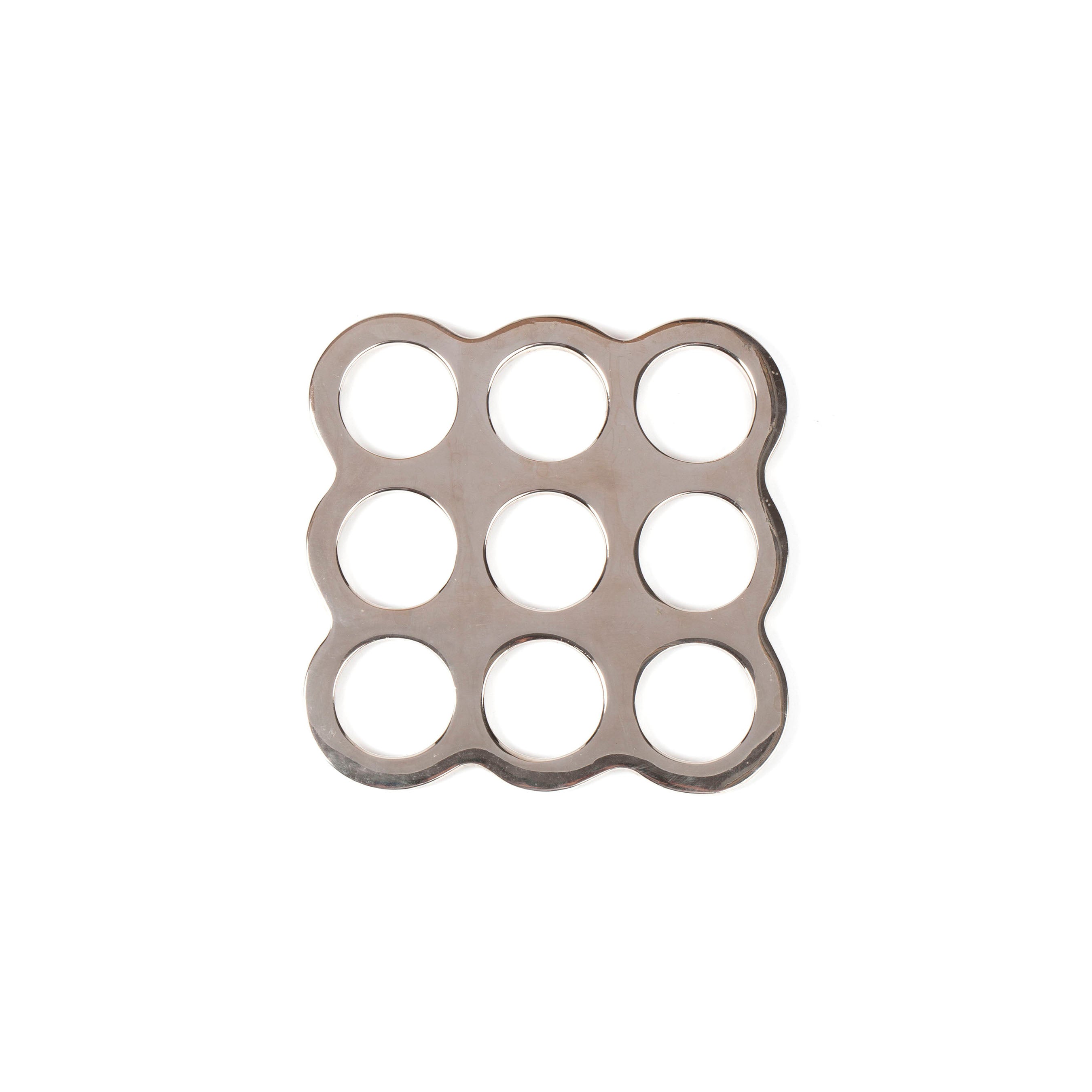 The Coaster #5506 by Werkstätte Carl Auböck features a metal grid with nine circular holes in a 3x3 pattern, echoing the brands innovative Viennese designs. The slightly wavy edges and shiny stainless steel stand out against the white background.