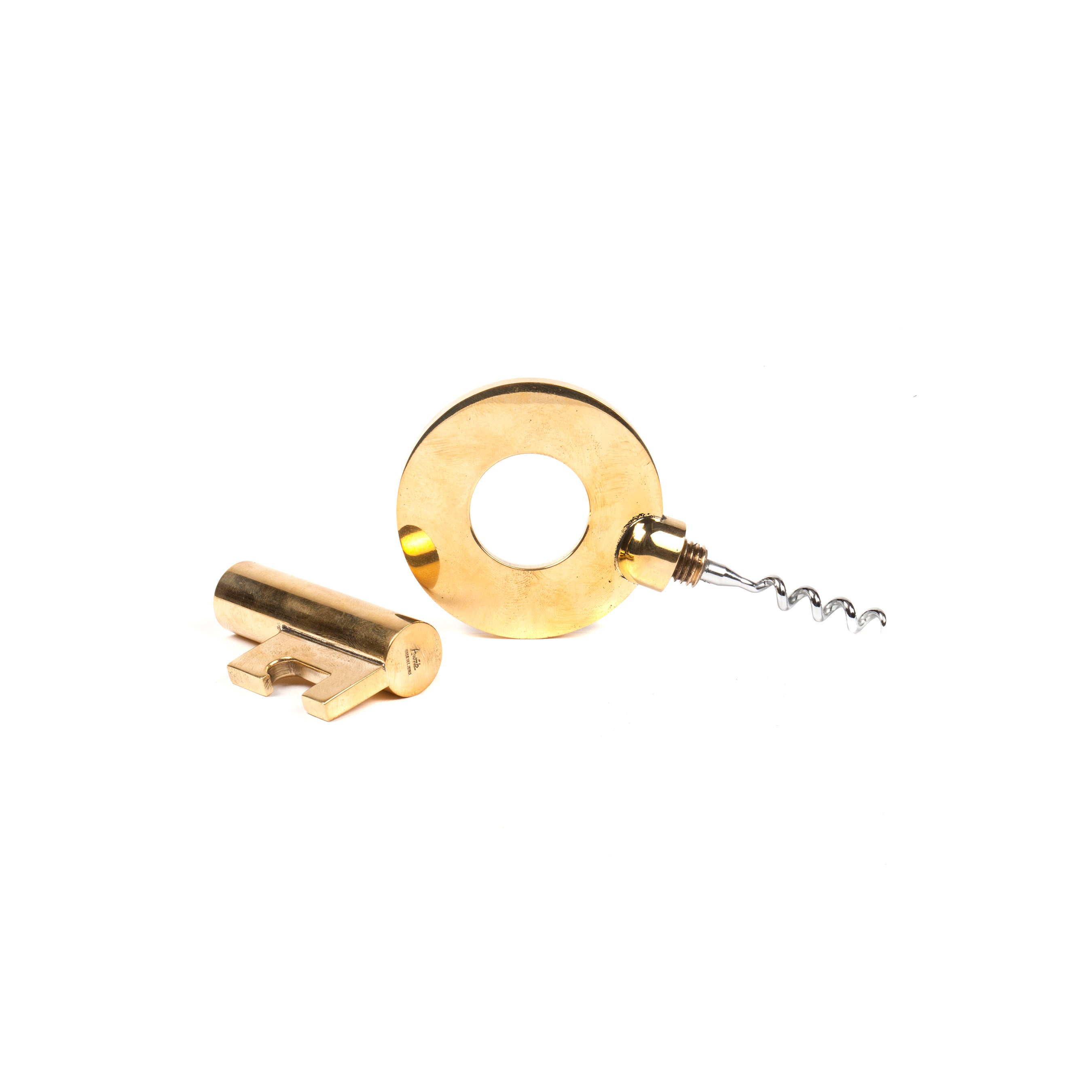 The Gold-toned two-piece set, named Corkscrew Key #5970 from Werkstätte Carl Auböck, includes a round bottle opener with a central hole and a corkscrew. Accompanied by a key-shaped opener, it showcases the timeless elegance and meticulous craftsmanship of Auböck against a white background.