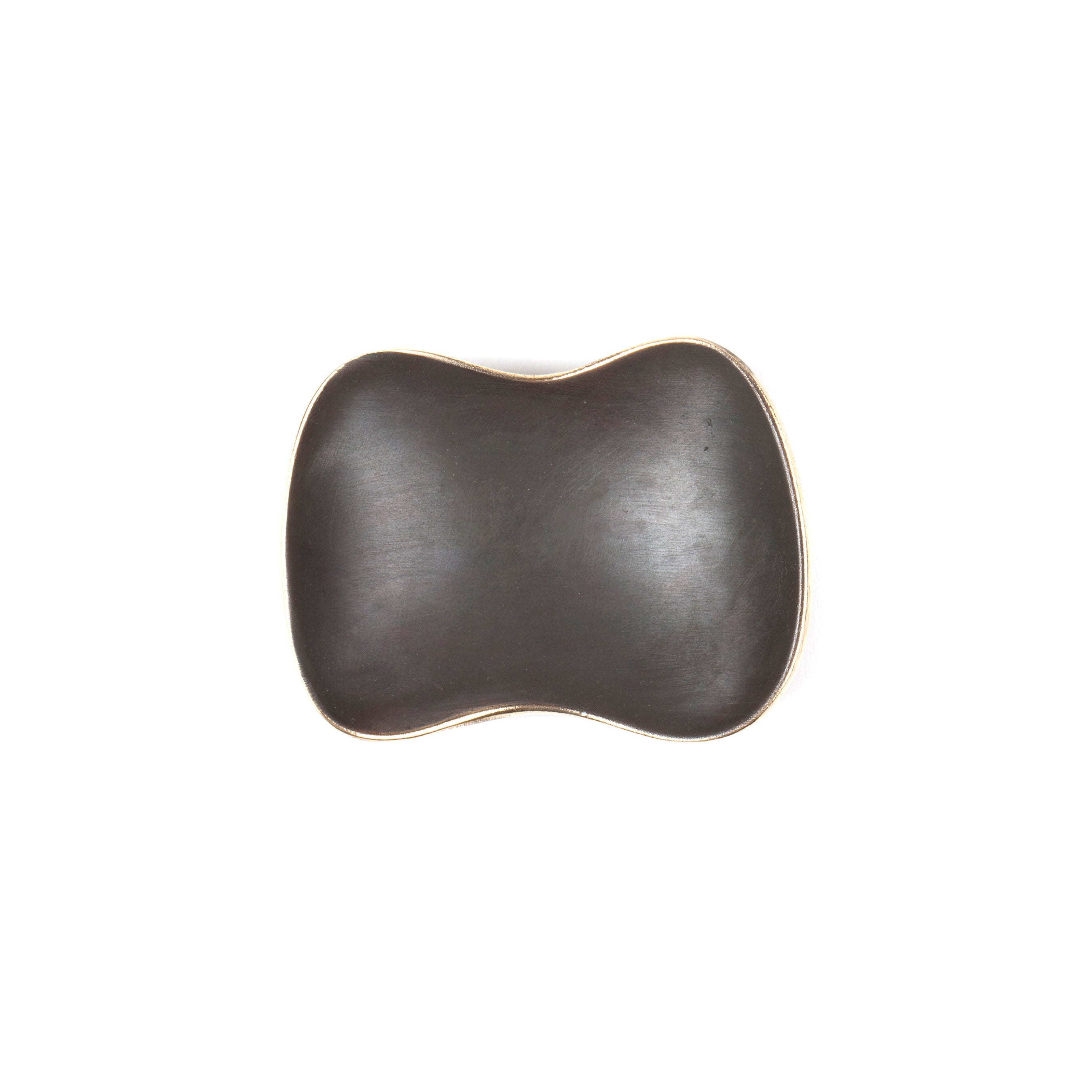 A black, irregularly shaped ceramic bowl with a wavy, organic form reminiscent of an Auböck design is depicted from above on a white backdrop. The edges are slightly lighter, offering subtle contrast. Product: Dish #3979 by Werkstätte Carl Auböck.