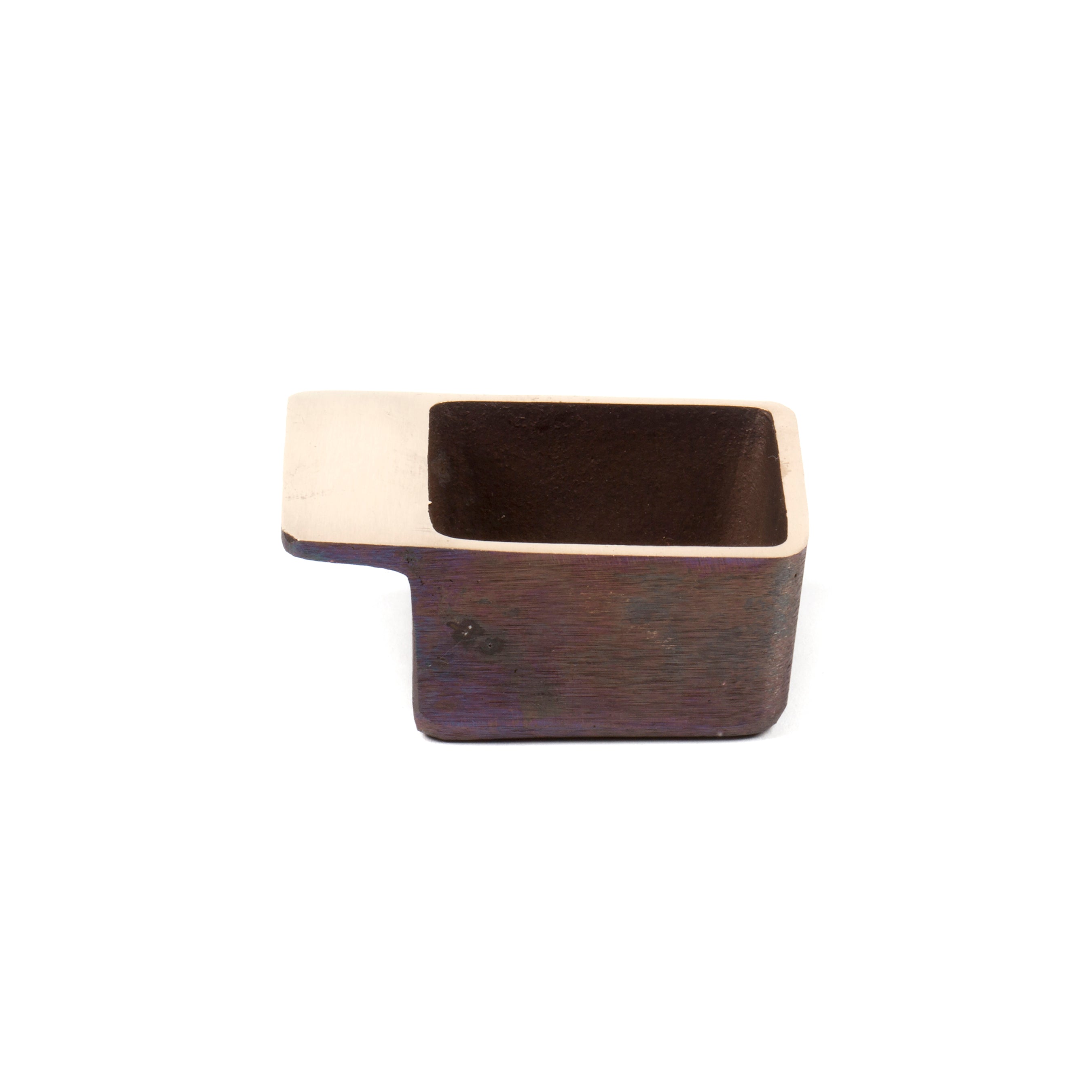The Ashtray #4610 by Werkstätte Carl Auböck is a small, rectangular metal cup with a flat, extended lip. Its dark brown exterior contrasts with the lighter metallic top edge and lip, echoing the classic style of Viennese Wiener Bronzen.