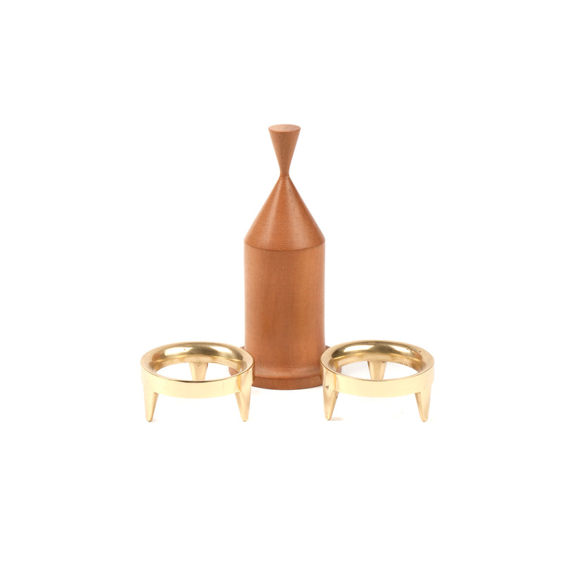 A wooden, bottle-shaped container with a pointed top channels Carl Auböcks style, elegantly standing between two Wiener Bronzen egg cups (Egg Cups Set #3697 by Werkstätte Carl Auböck) in gold with three legs each, set against a pristine white background.