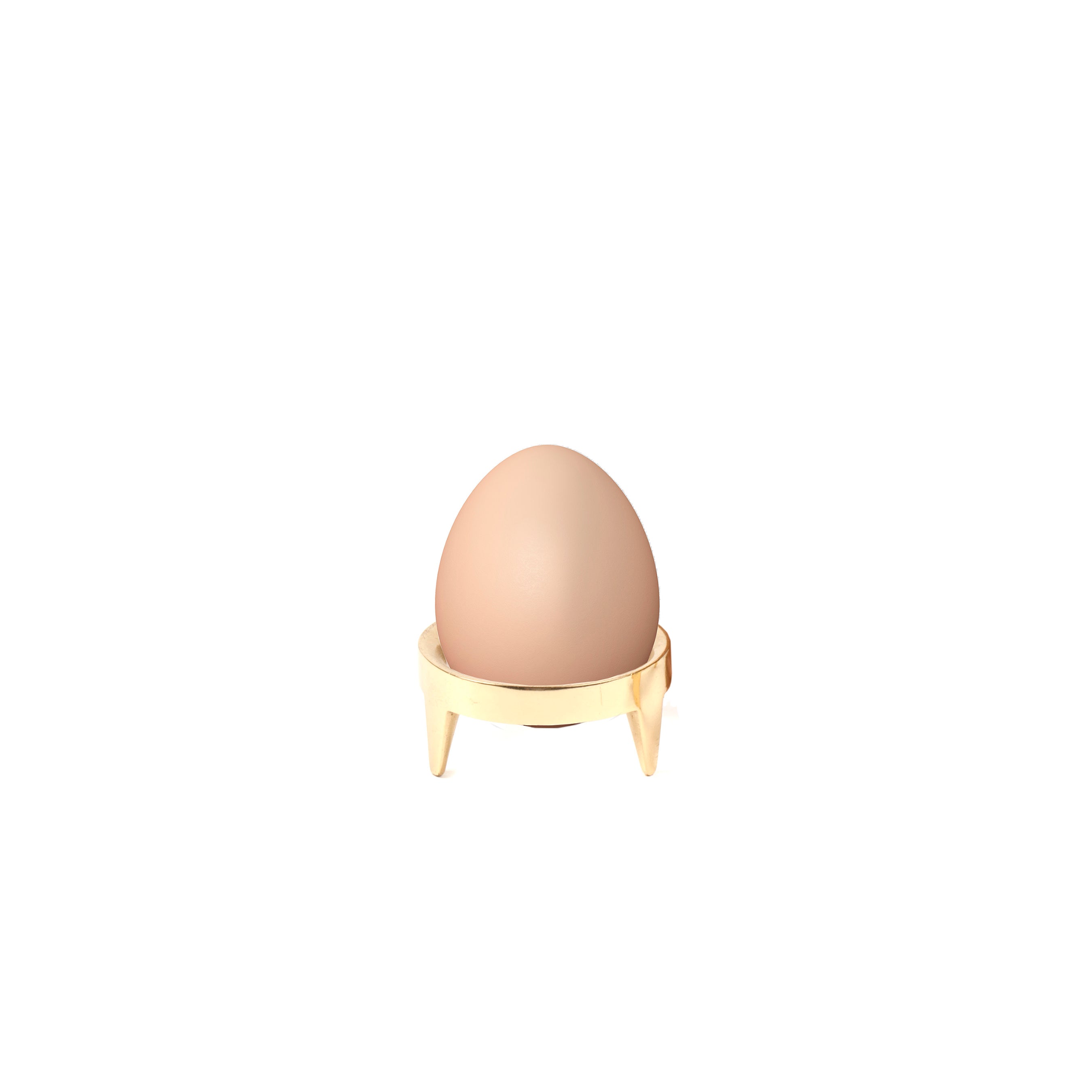 A single light brown egg stands upright in a beige Egg Cup #3697 by Werkstätte Carl Auböck, echoing timeless Viennese design against a plain white background.