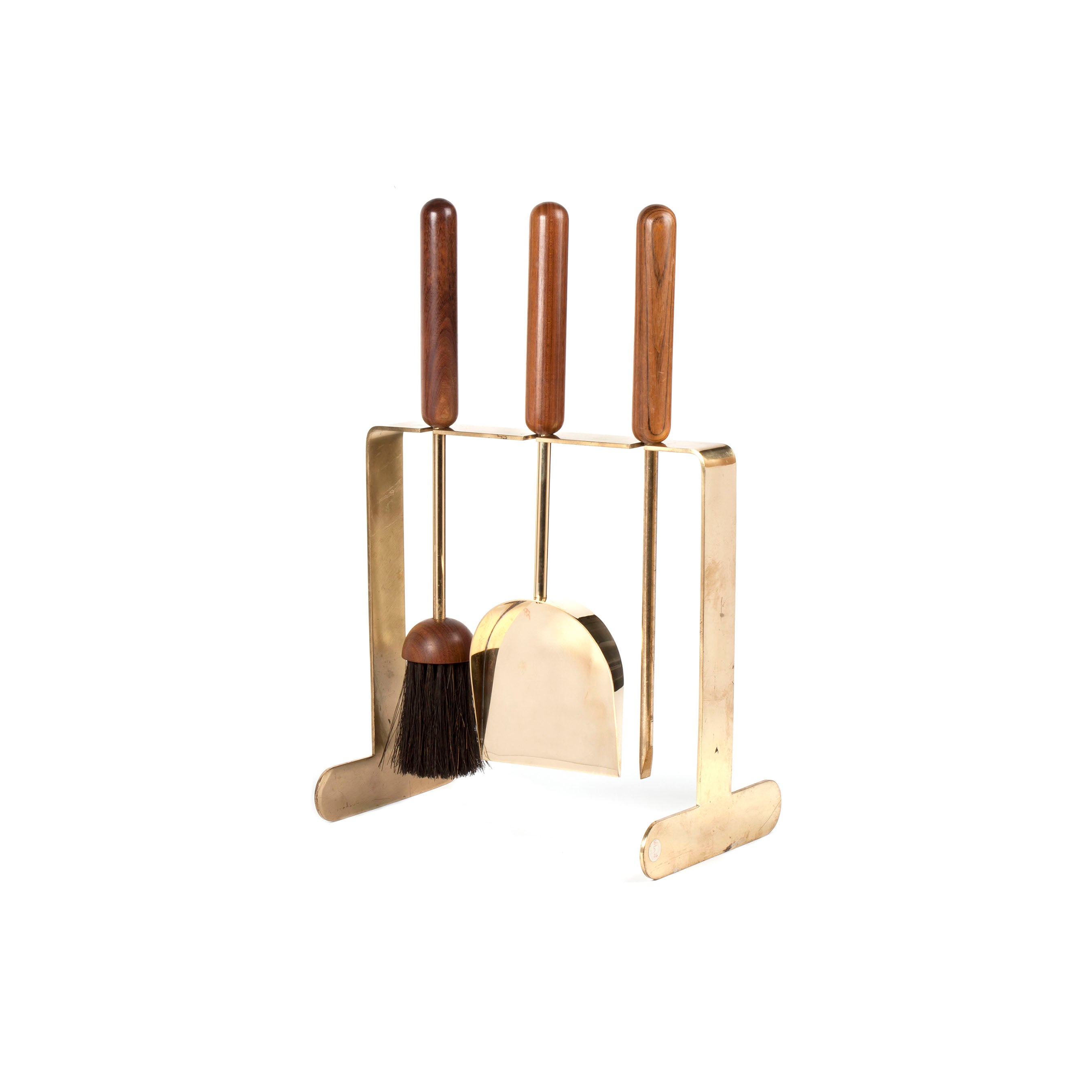 The Fireplace set #6090 by Werkstätte Carl Auböck features three stylish brass tools with wooden handles, including a brush, shovel, and poker on an elegant stand. Perfect for evoking the charm of a Viennese townhouse against a plain white backdrop.