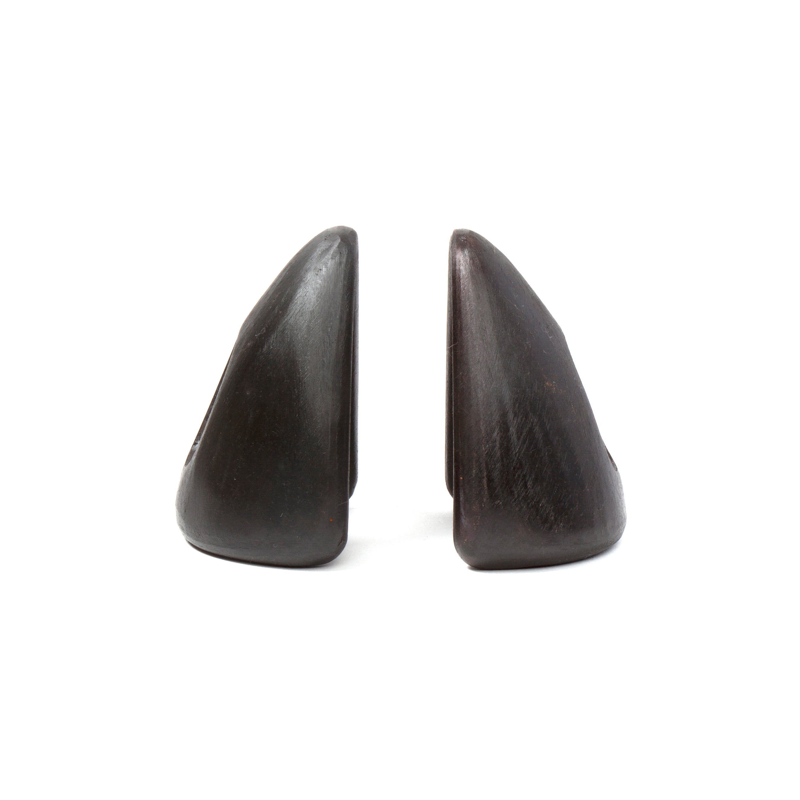 Two dark, triangular stone sculptures, named Pair of Bookends #4635 by Werkstätte Carl Auböck, stand upright side by side like abstract mountain peaks against a white background. Their smooth surfaces evoke elegance with subtle variations in color and texture.