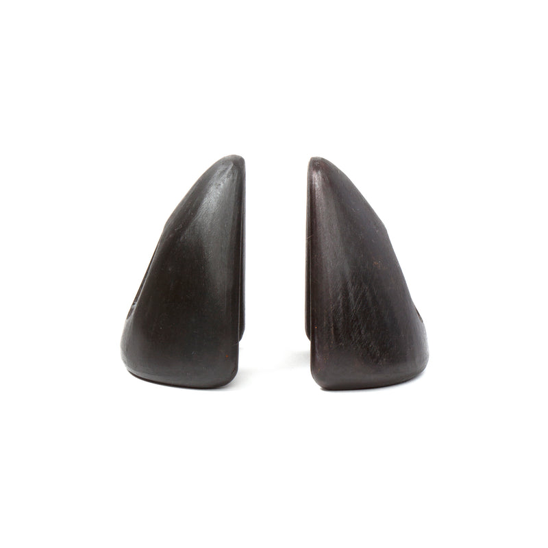 Two dark, triangular stone sculptures, named Pair of Bookends #4635 by Werkstätte Carl Auböck, stand upright side by side like abstract mountain peaks against a white background. Their smooth surfaces evoke elegance with subtle variations in color and texture.