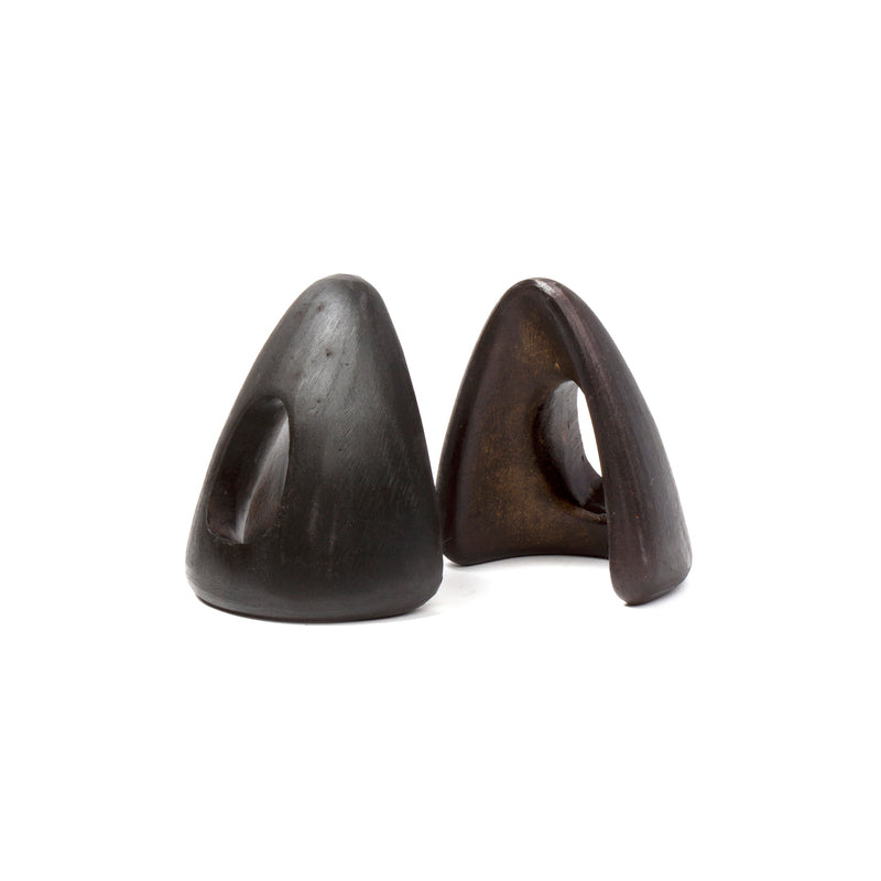 The Pair of Bookends #4635 by Werkstätte Carl Auböck are dark, smooth, conical ceramic sculptures with circular cutouts; the left one is slightly taller and the right has a pronounced curve. Both have a matte finish and rest on a plain white background.