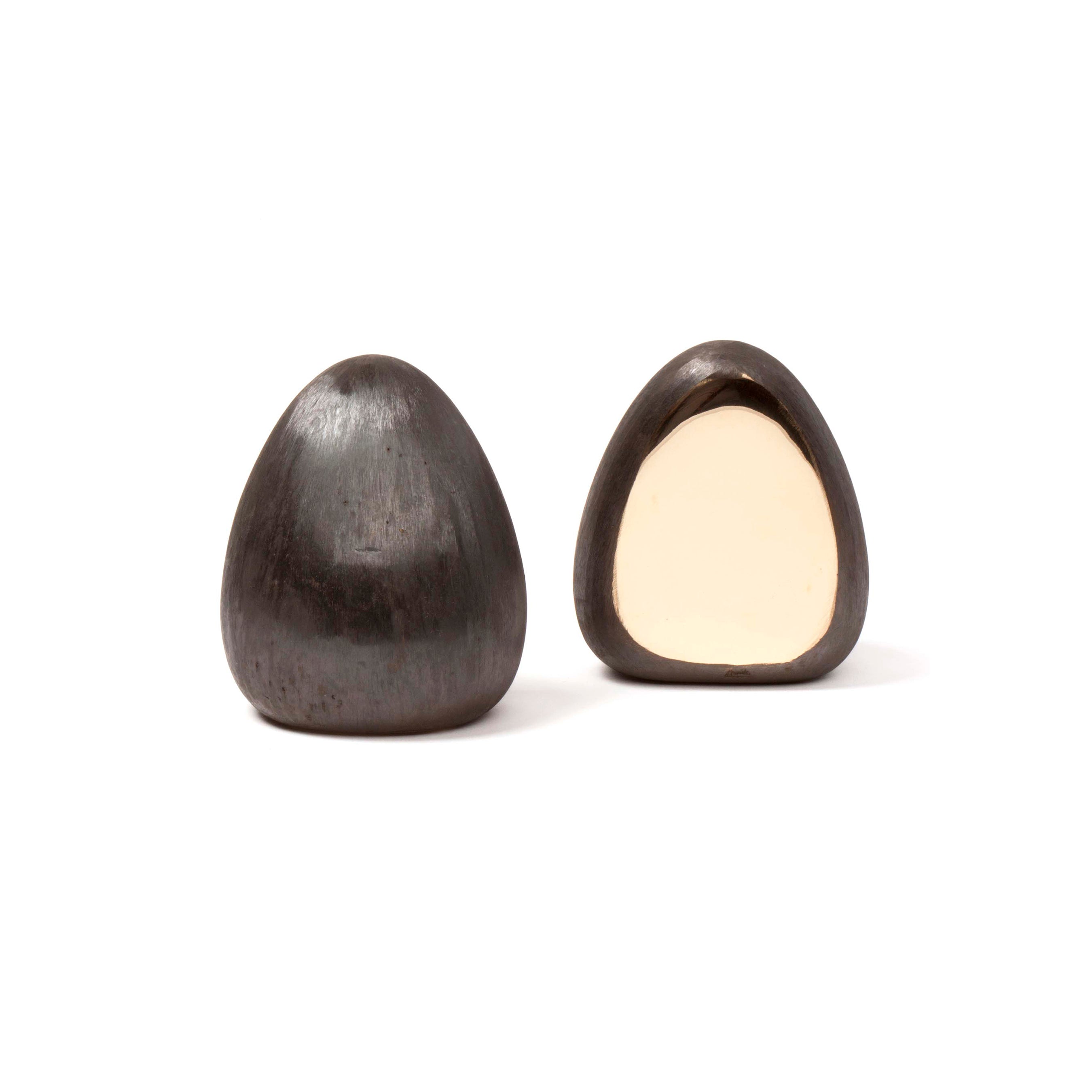 The Pair of Bookends #4636 by Werkstätte Carl Auböck features two smooth, dark brown teardrop stones; one whole and one split to reveal a creamy beige interior, embodying sculptural simplicity against a stark white background.