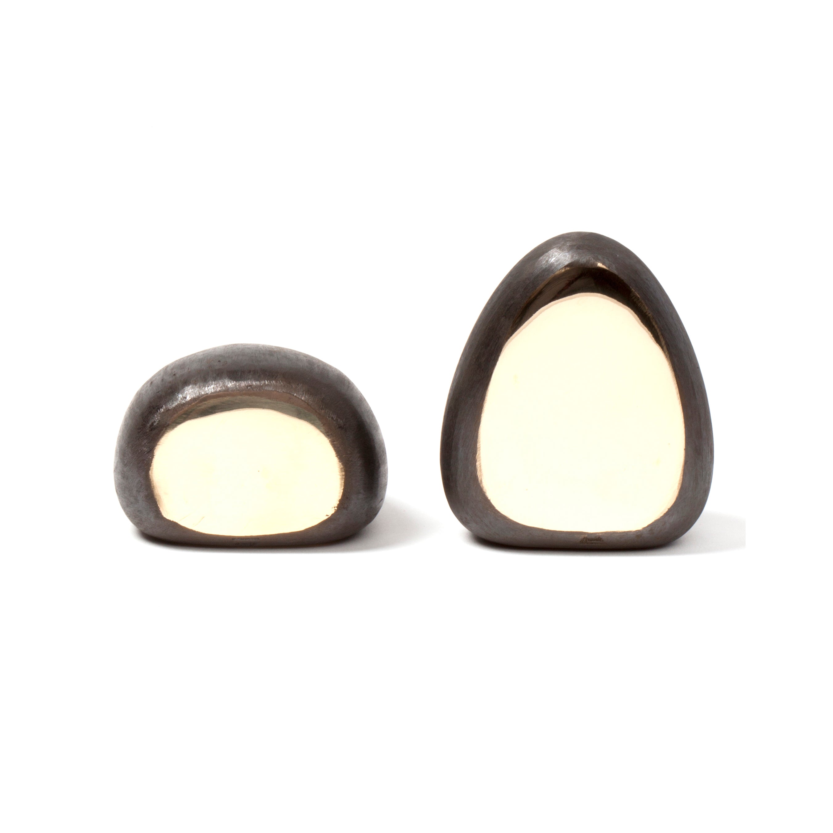 On a plain white backdrop, two chocolate-covered candies with creamy white centers are displayed. The smaller is rounder, the larger more triangular—reminiscent of the elegant design found in Werkstätte Carl Auböcks Pair of Bookends #4636.