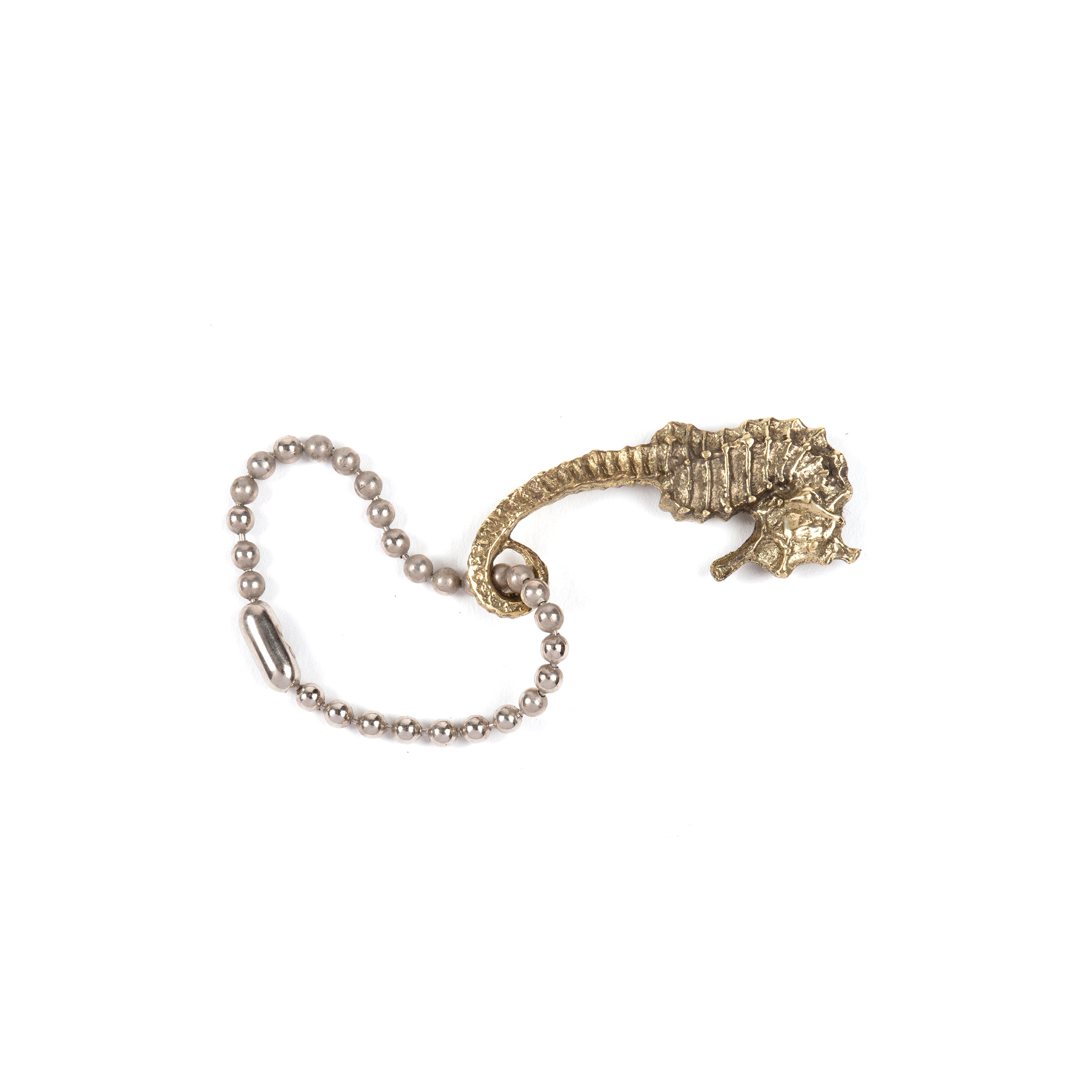The Keyring Seahorse #5655 by Werkstätte Carl Auböck features an intricately detailed metallic seahorse with a beaded chain, showcased against a plain white background, echoing the timeless elegance of a Viennese townhouse with its curved tail and textured body.