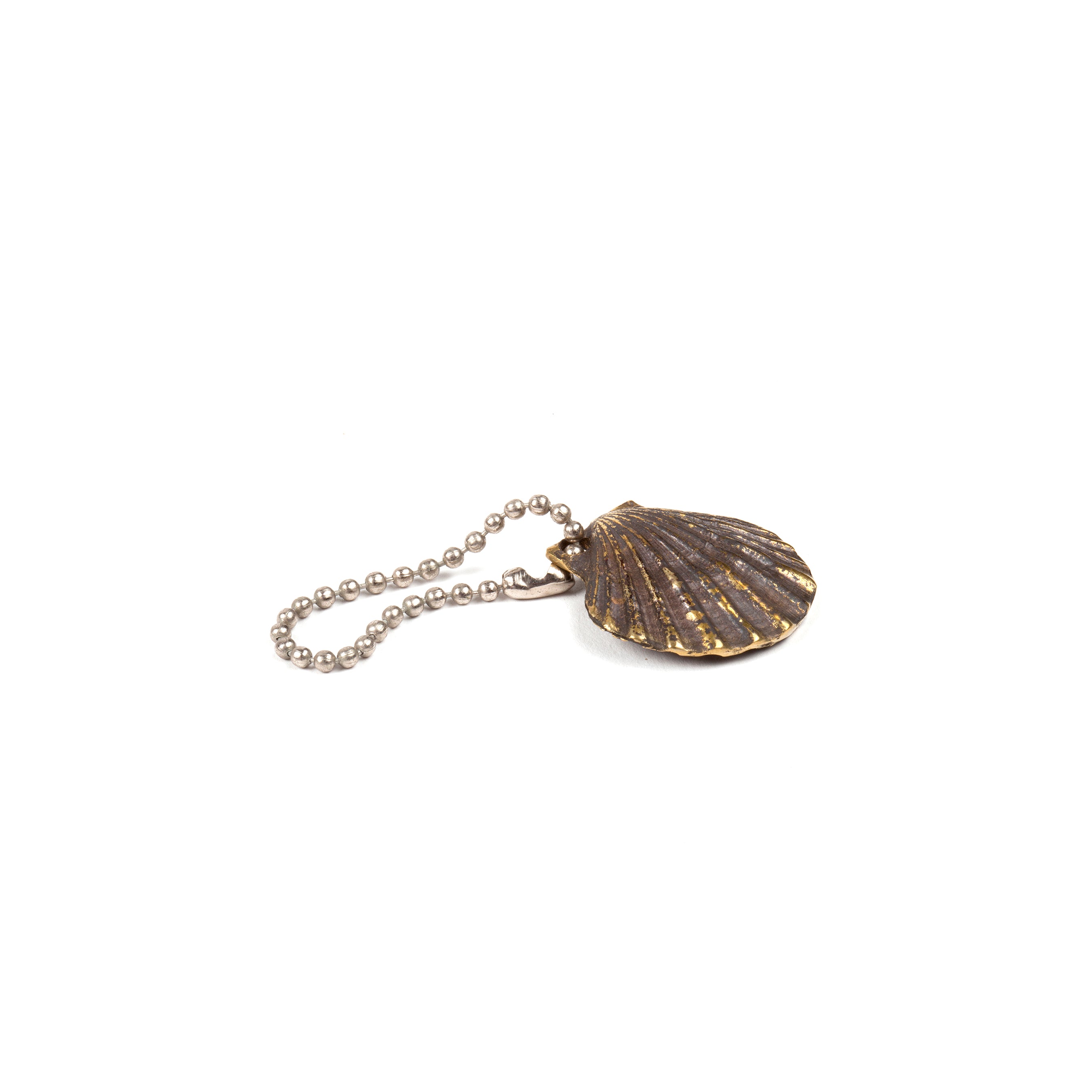 The Keyring Shell #5663 by Werkstätte Carl Auböck features a bronze-toned, shell-shaped pendant on a ball chain, set against a pristine white background.