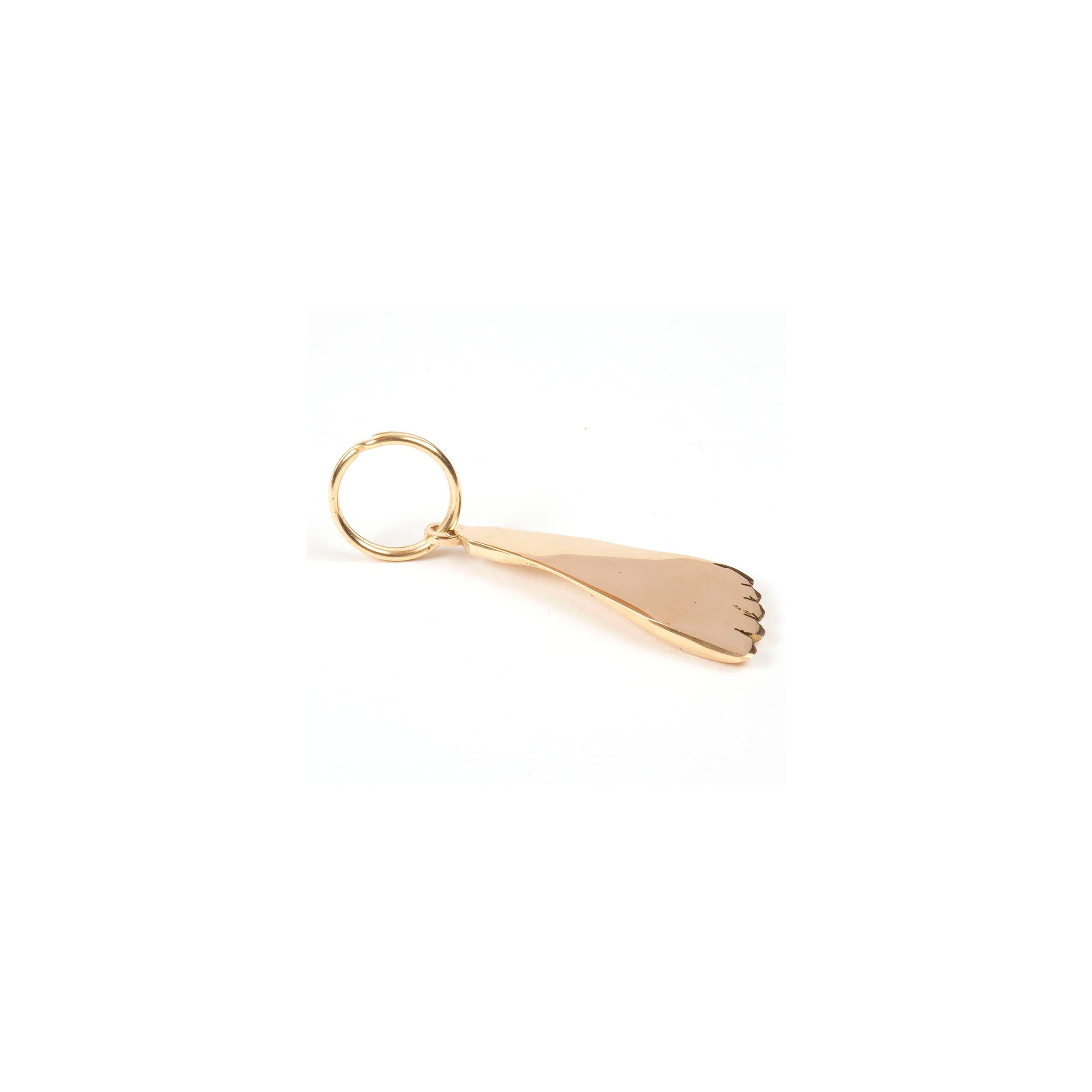 The Keyring Foot #5735 by Werkstätte Carl Auböck is a gold-colored keychain shaped like a human foot, attached to a circular keyring on a white background.