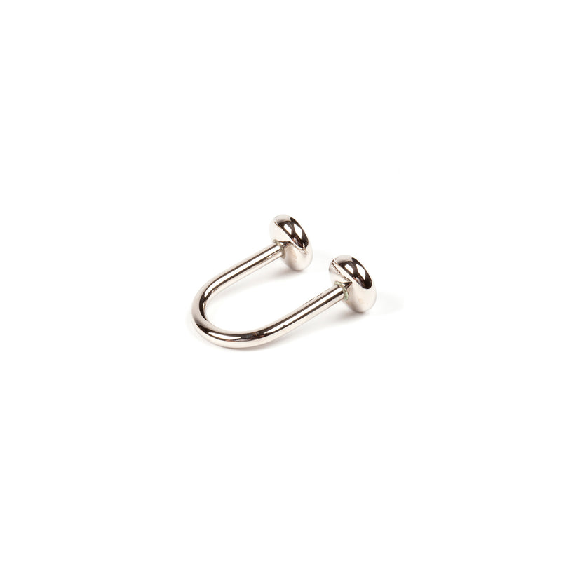 A horseshoe-shaped keyring from Werkstätte Carl Auböck, resembling a silver septum ring with rounded ends, stands out against a plain white background.
